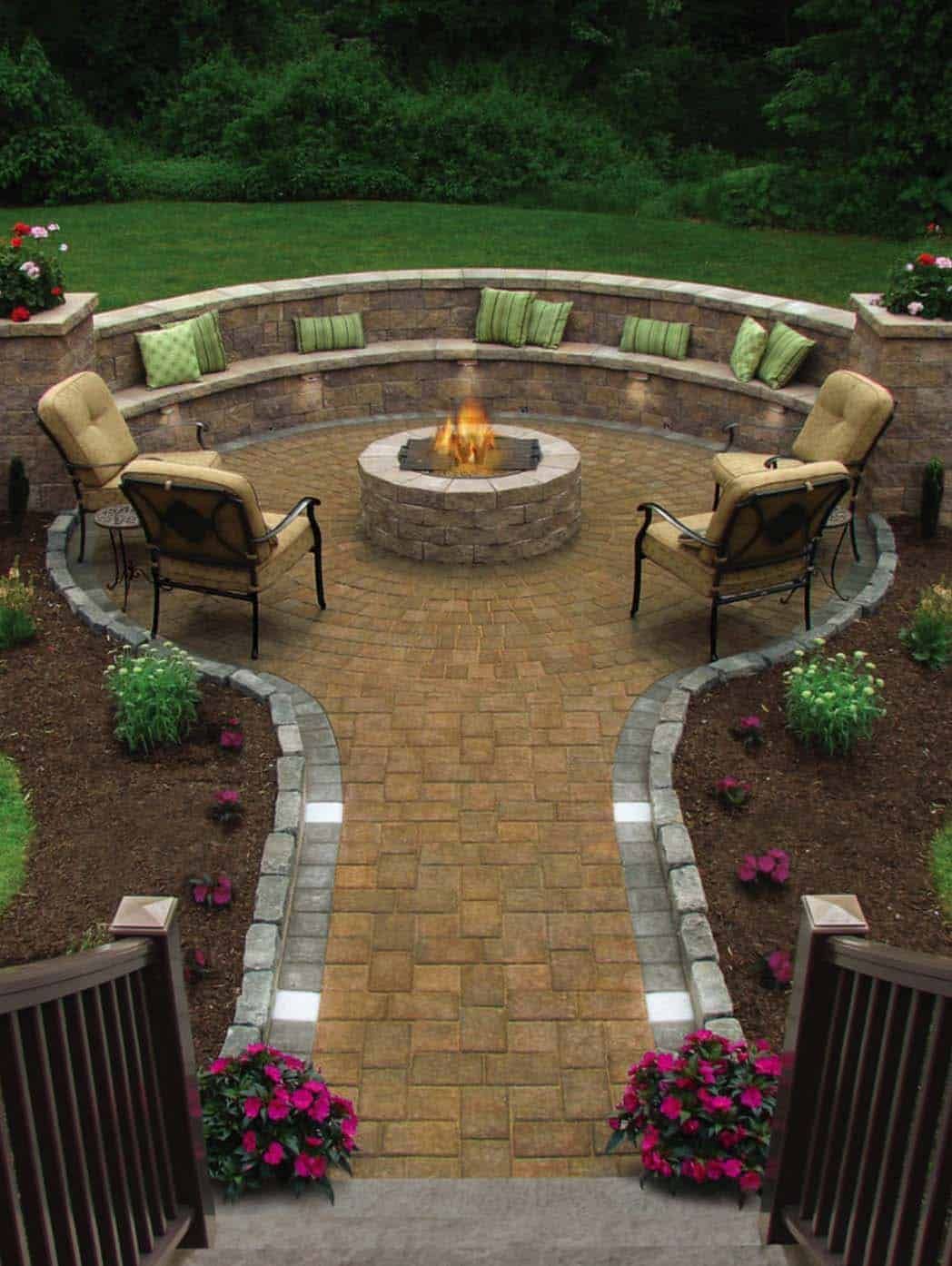 Stone patio with fire pit, seating, and pathway leading from wooden stairs, surrounded by landscaping.