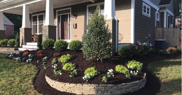 Landscaped yard with a circular garden bed in front of a house.