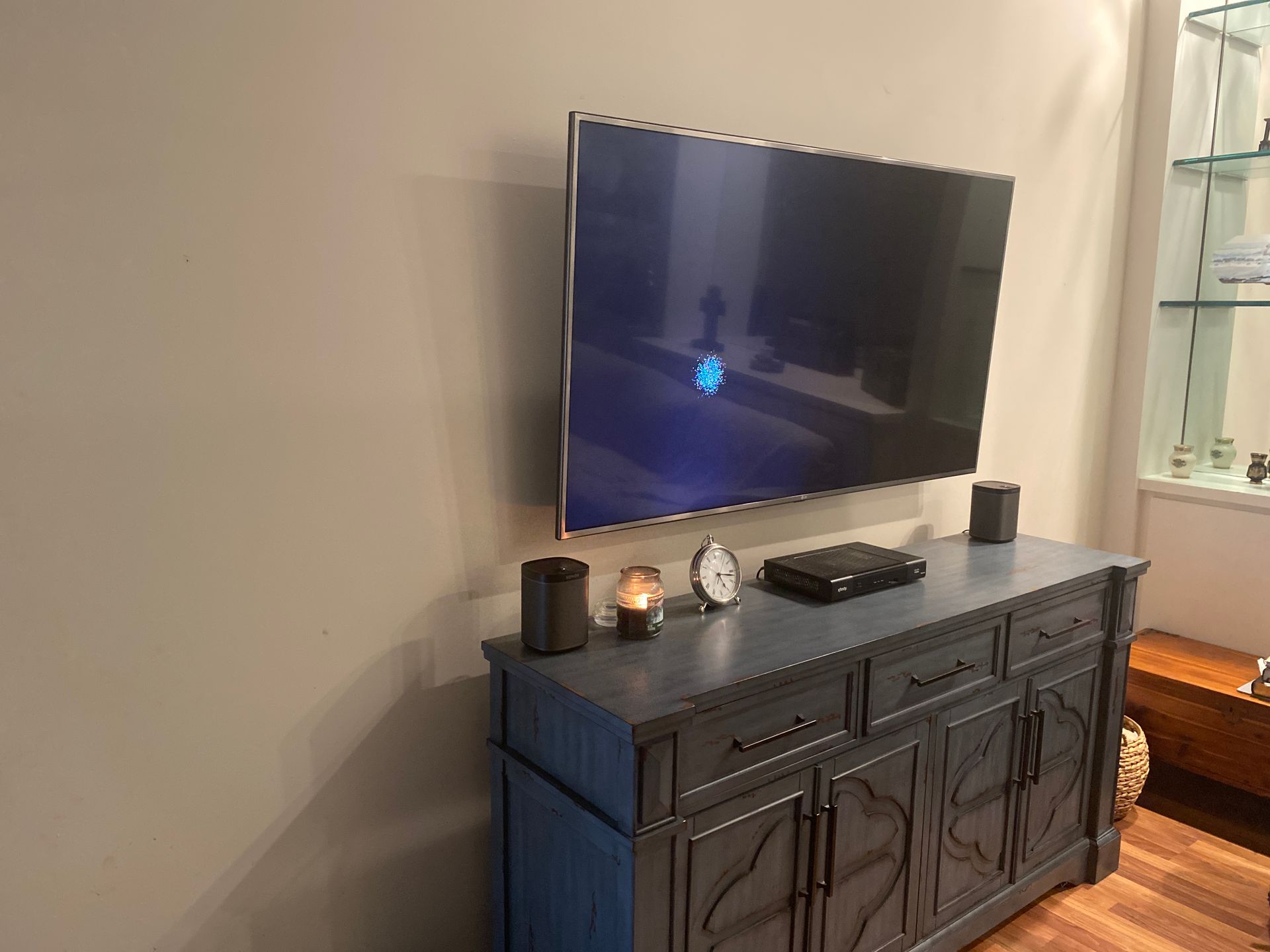 A flat screen tv is mounted on a wall above a blue dresser.