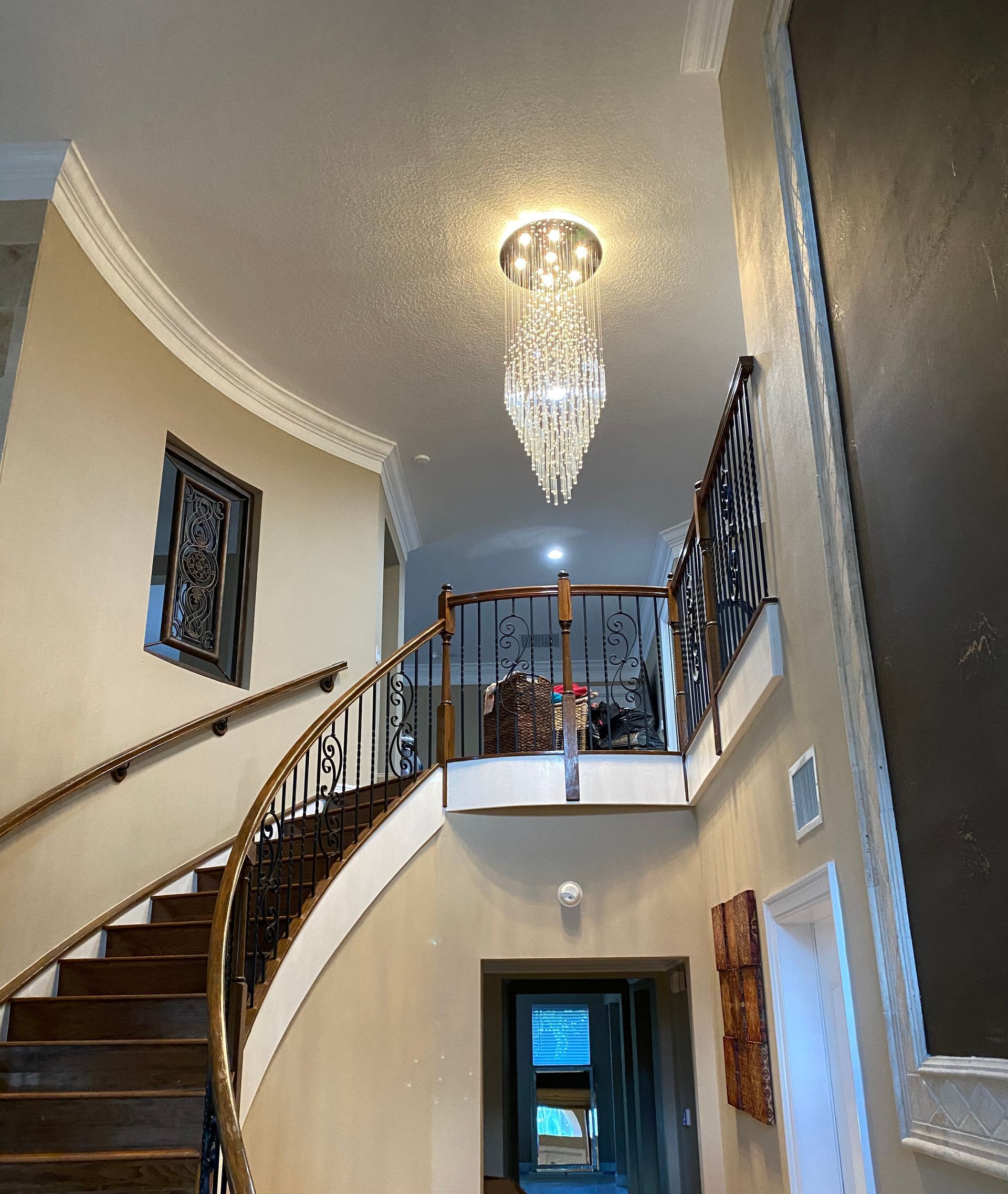 A man is sitting on a ladder working on a chandelier.