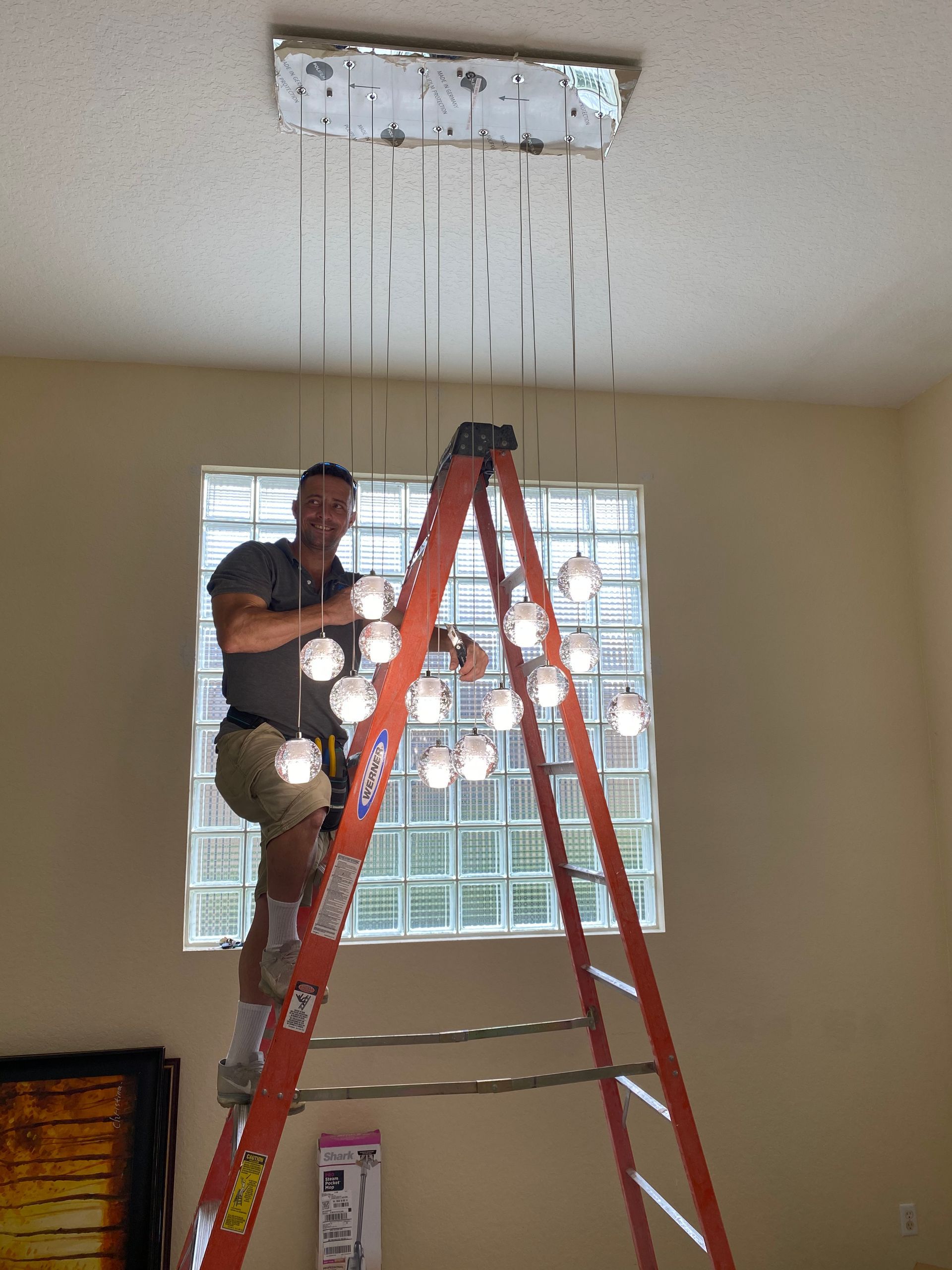 A man on a ladder working on a chandelier
