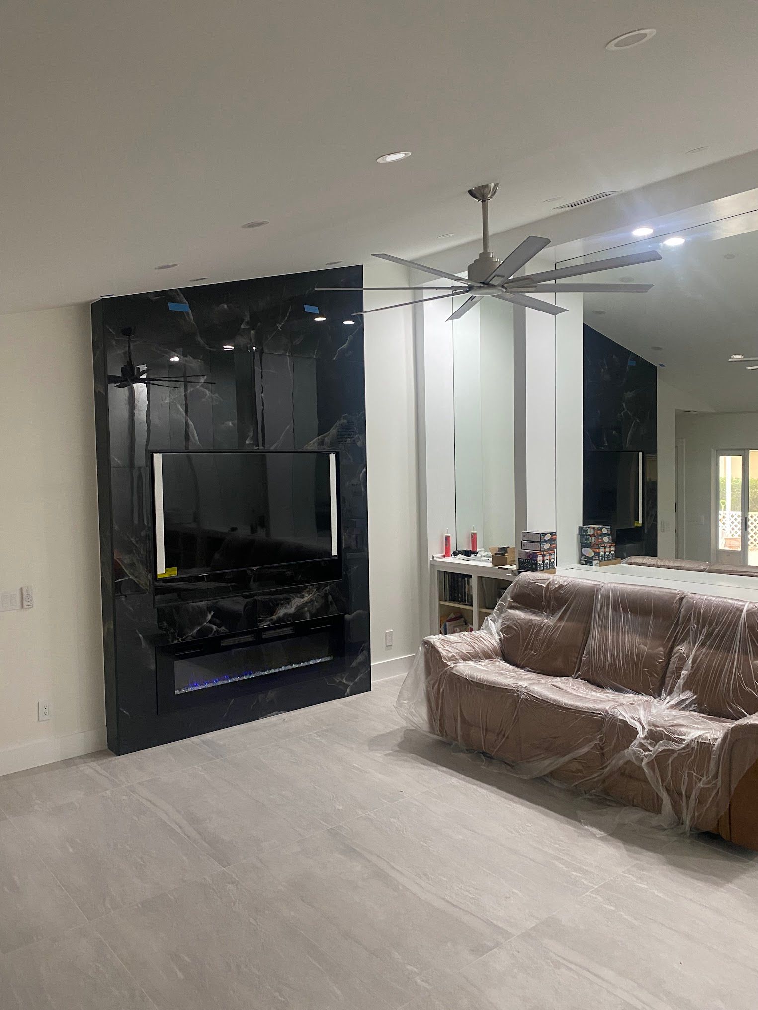 A living room with a couch , television , and ceiling fan.