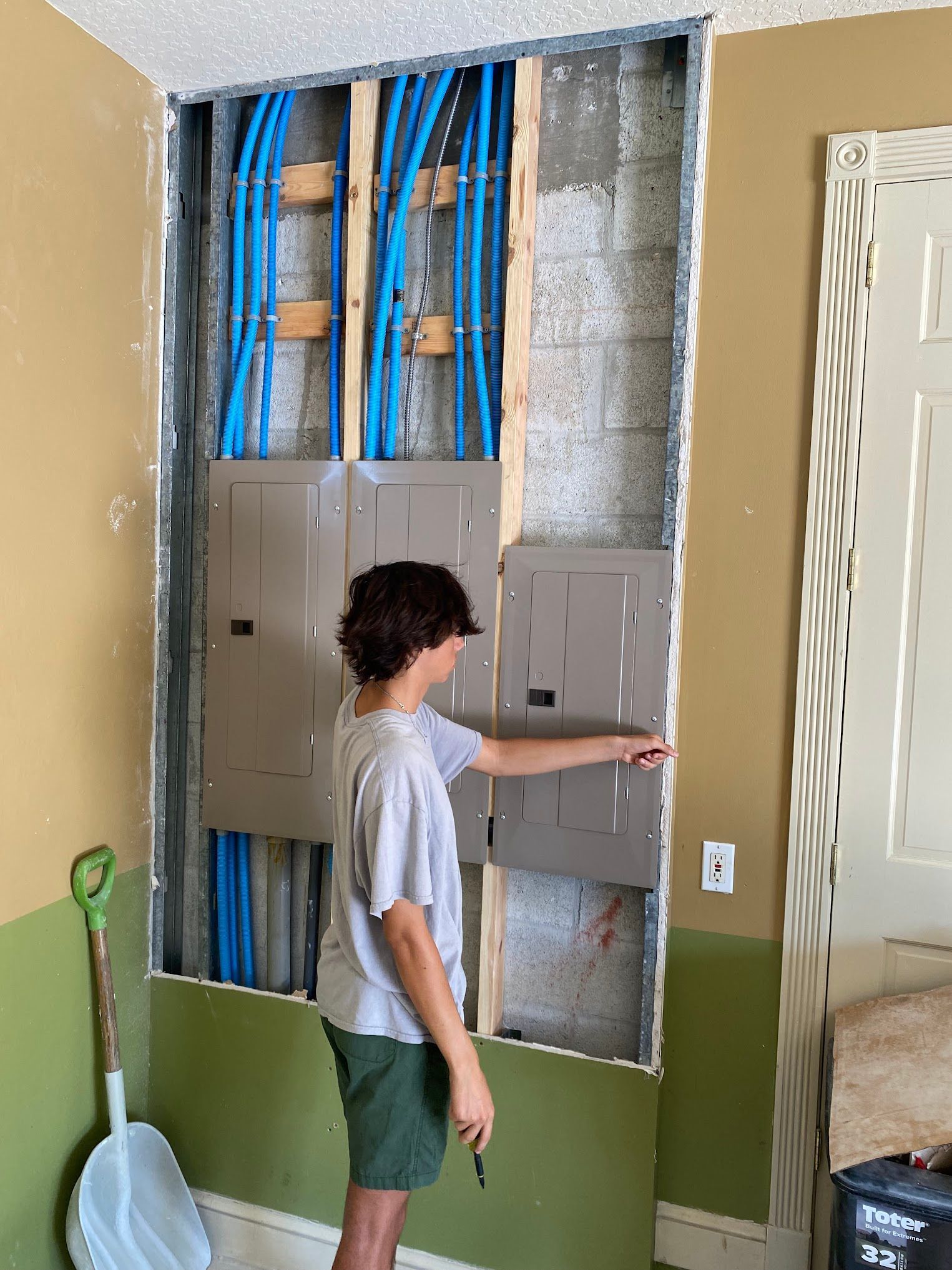 A young boy is standing in front of a wall with electrical panels.