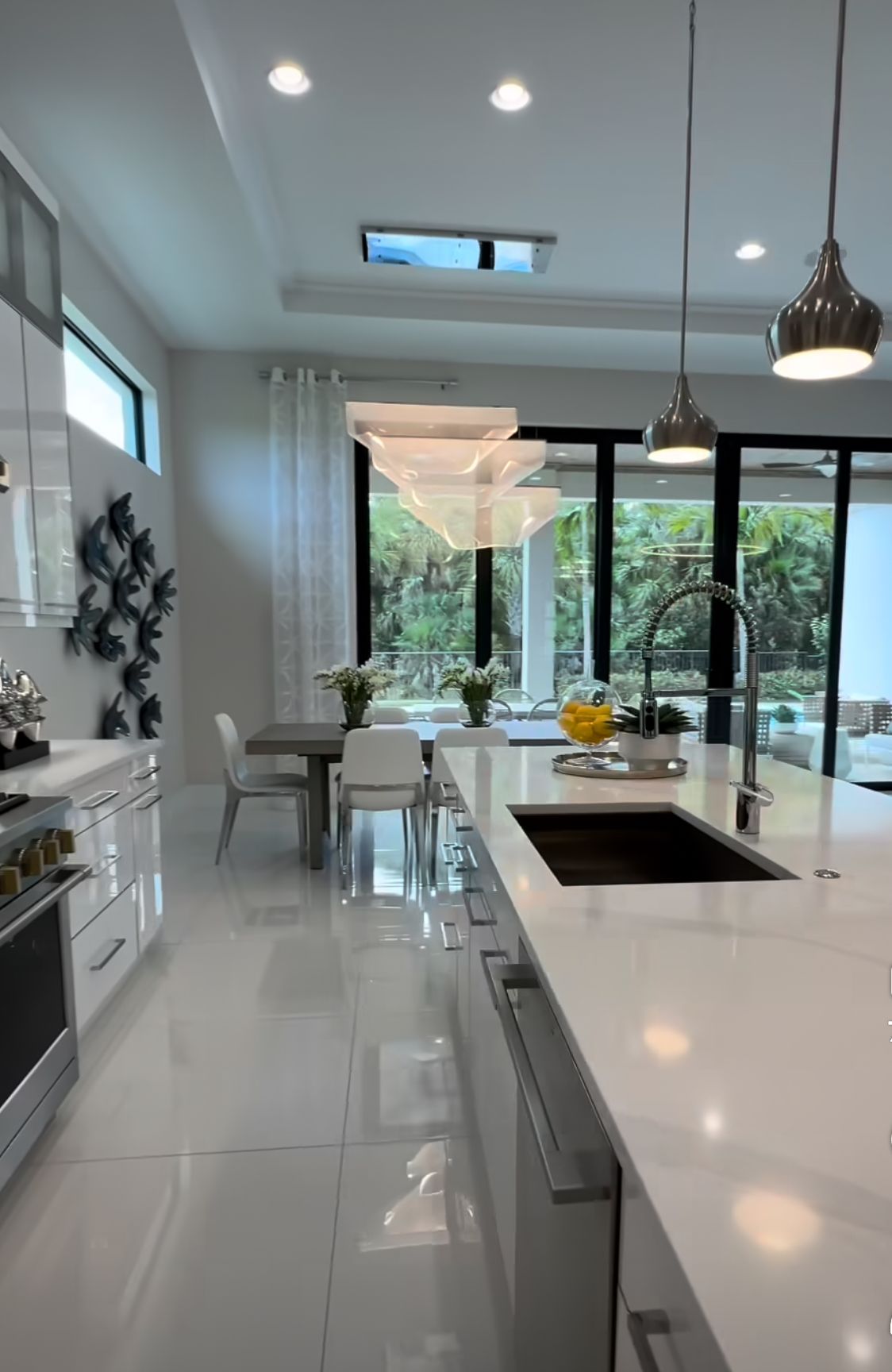 A kitchen with white cabinets , a sink , a table and chairs.