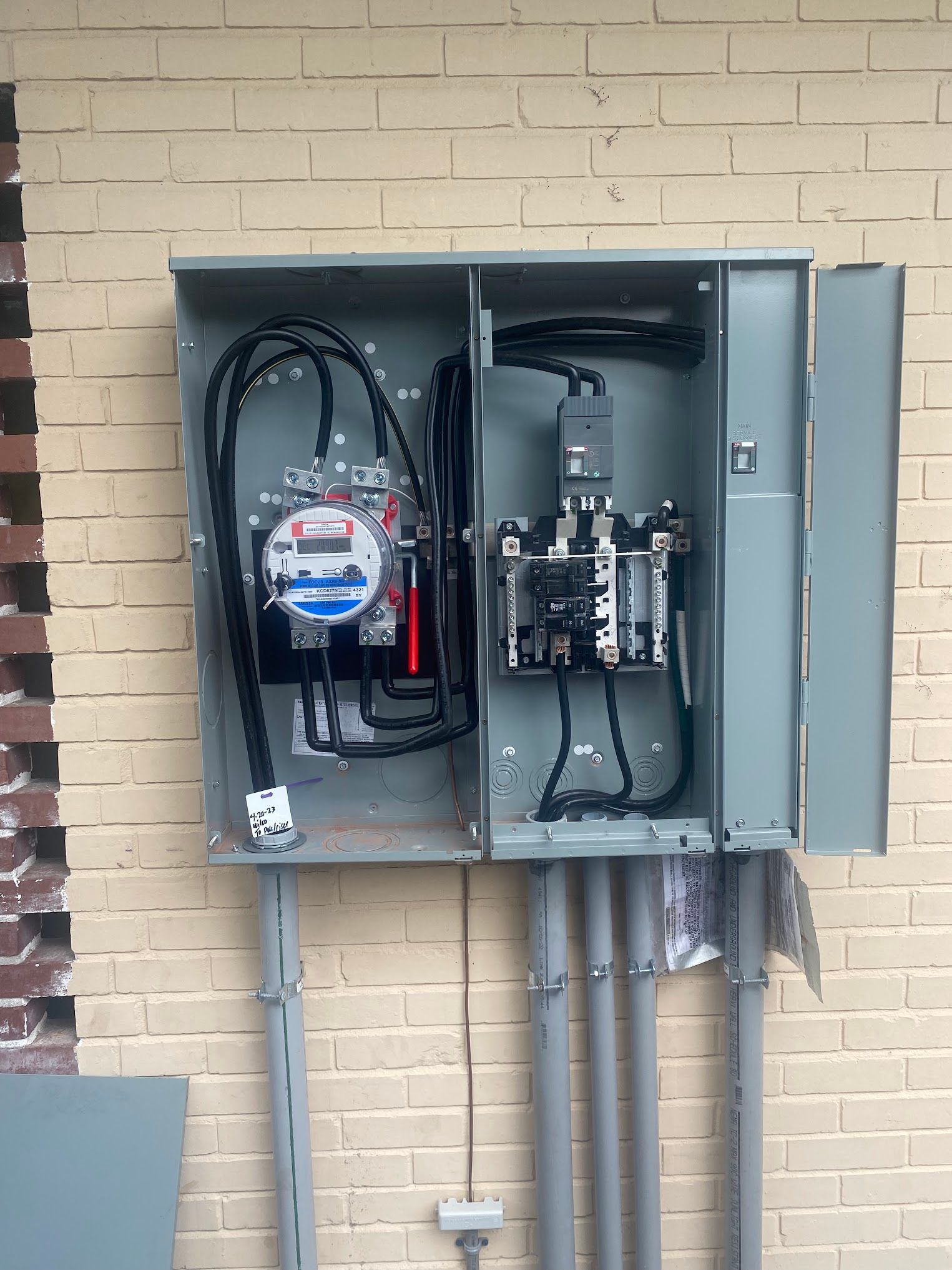 A electrical box with a meter inside of it on a brick wall.