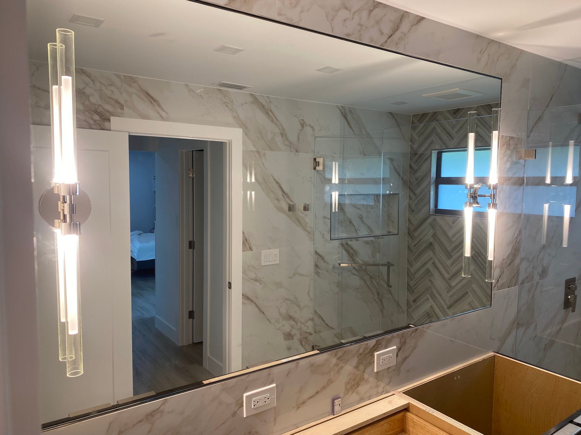 A bathroom with a large mirror and two lights on the wall.