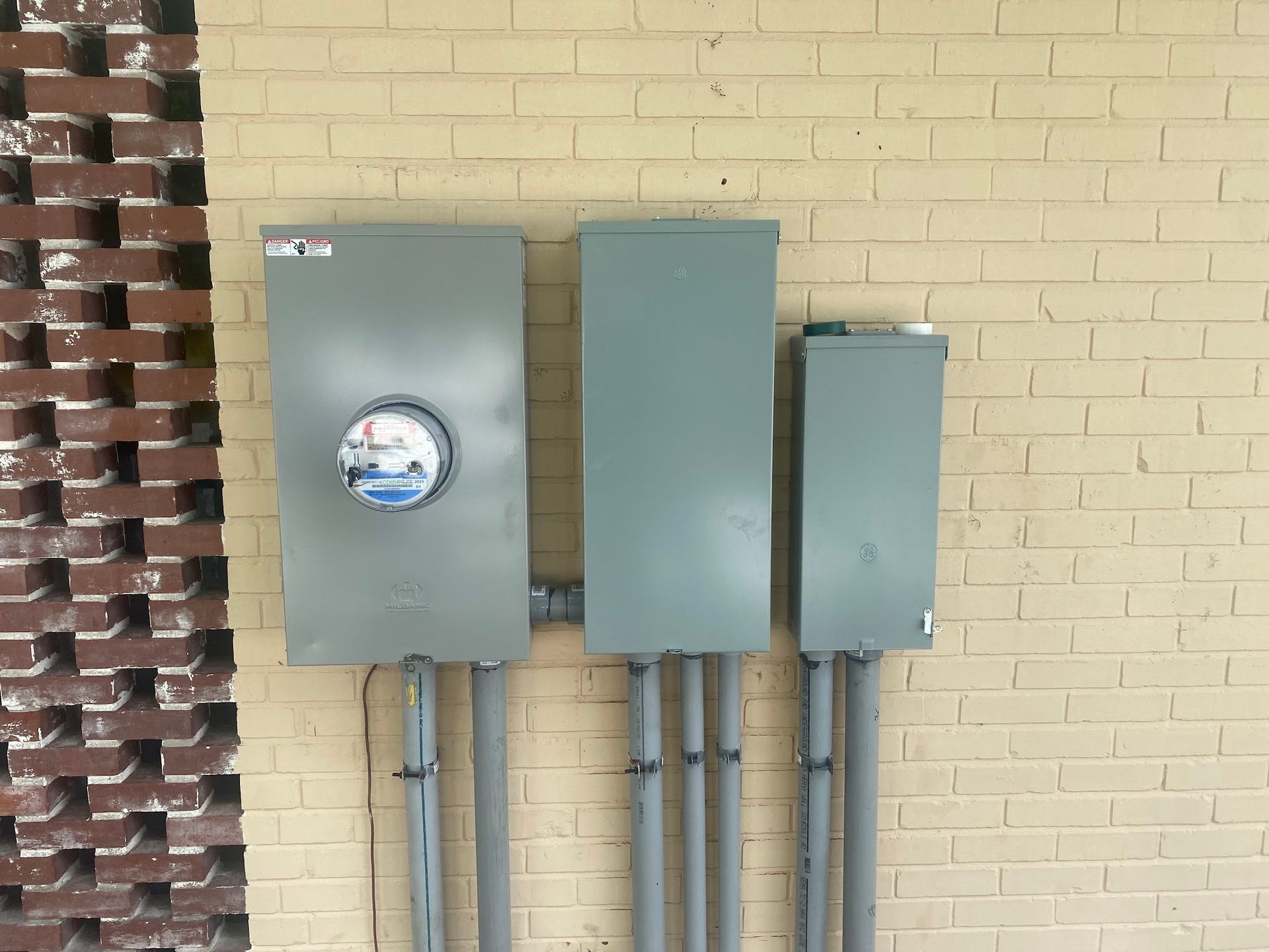 A brick wall with three electrical boxes attached to it