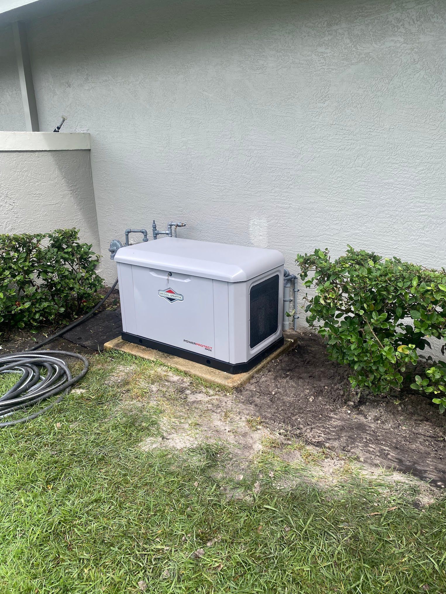 A generator is sitting in the grass next to a house.