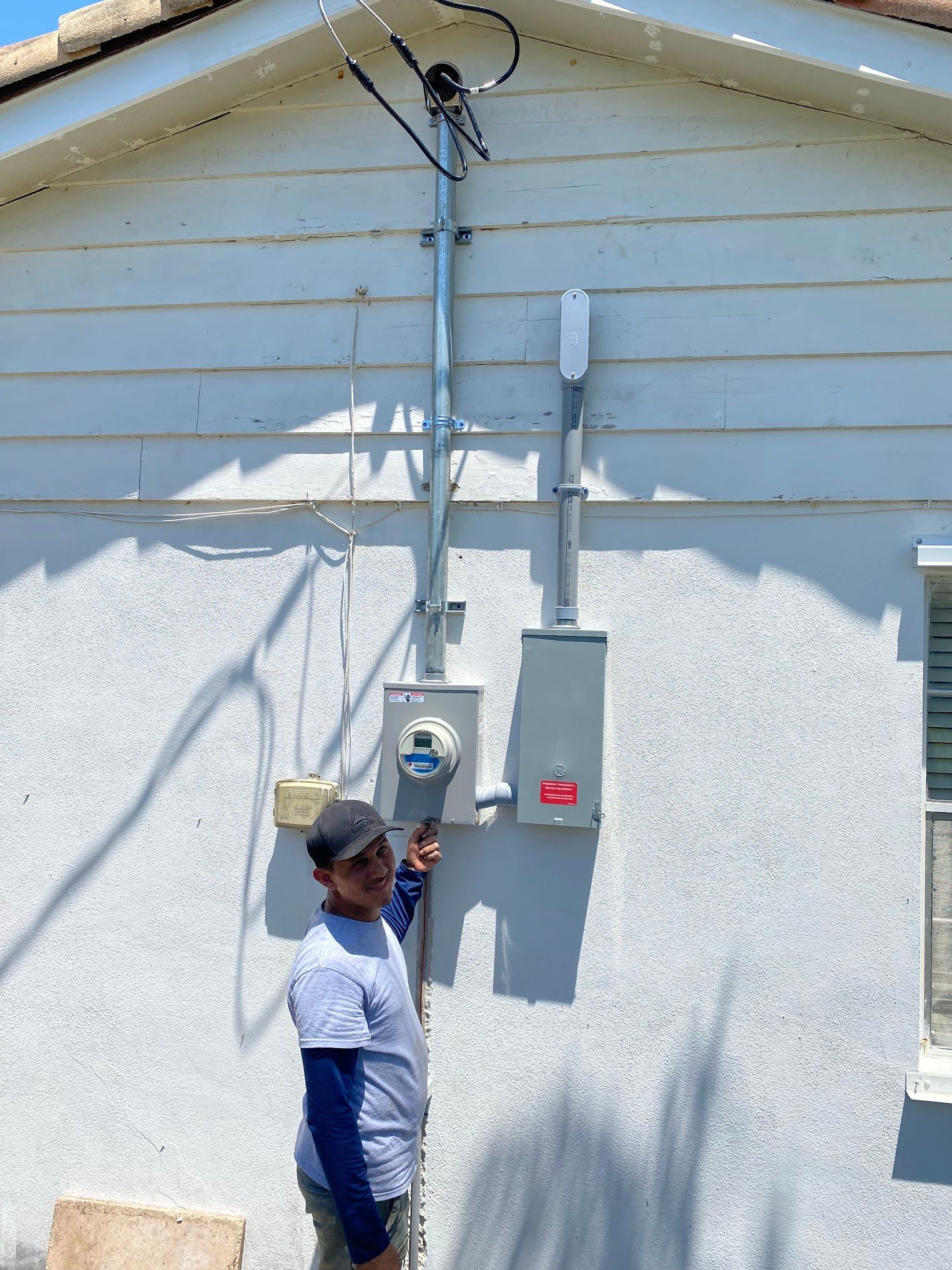A man is standing in front of a house with a meter on it.