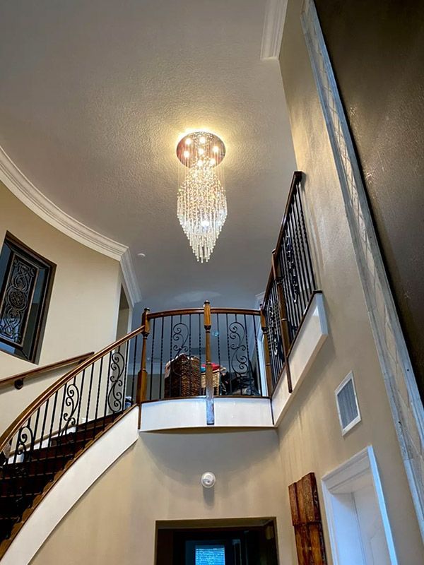 A staircase in a house with a chandelier hanging from the ceiling.