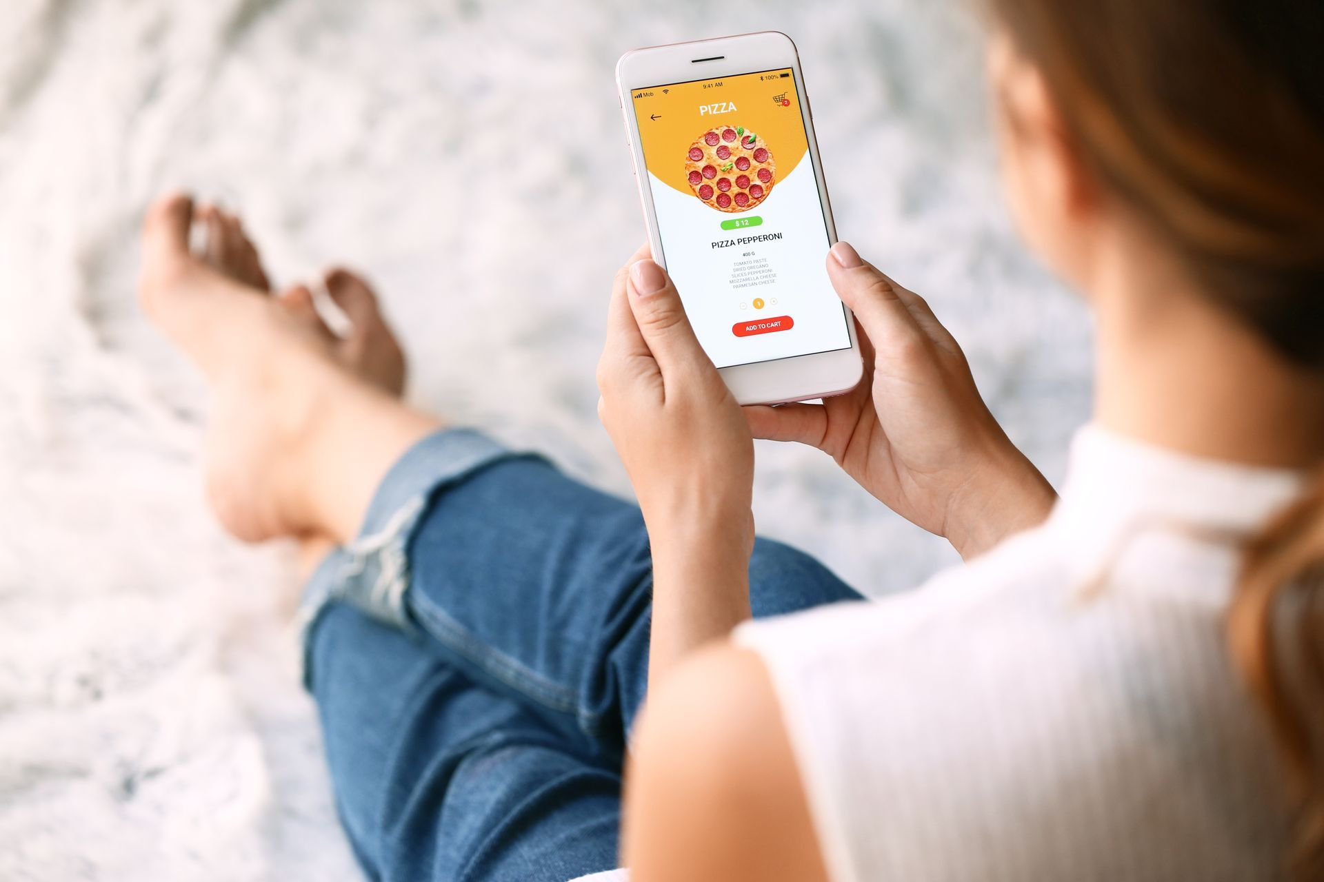 Woman using phone to order pizza; app screen showing pizza with toppings.
