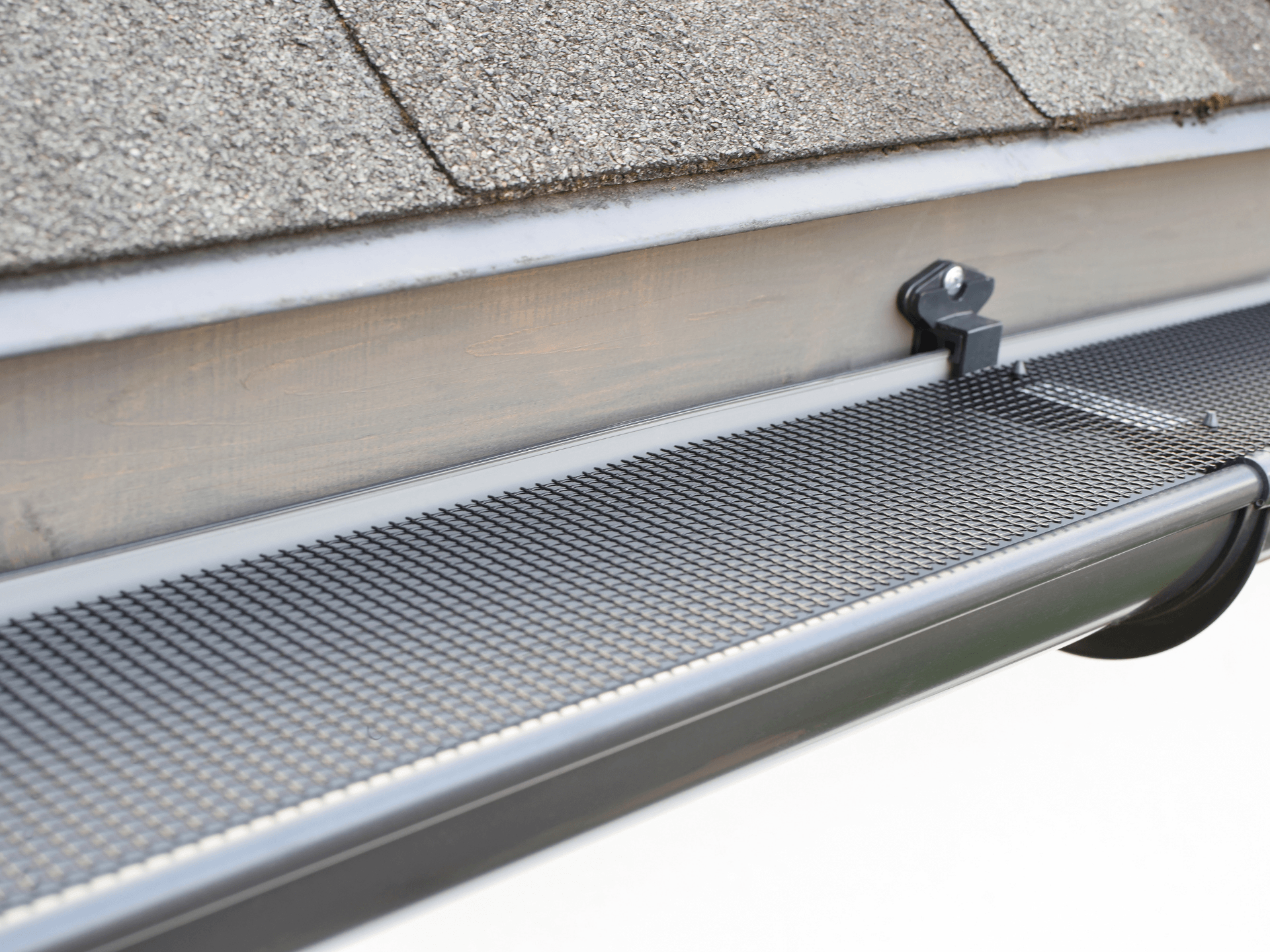 A close up of a gutter with a roof in the background