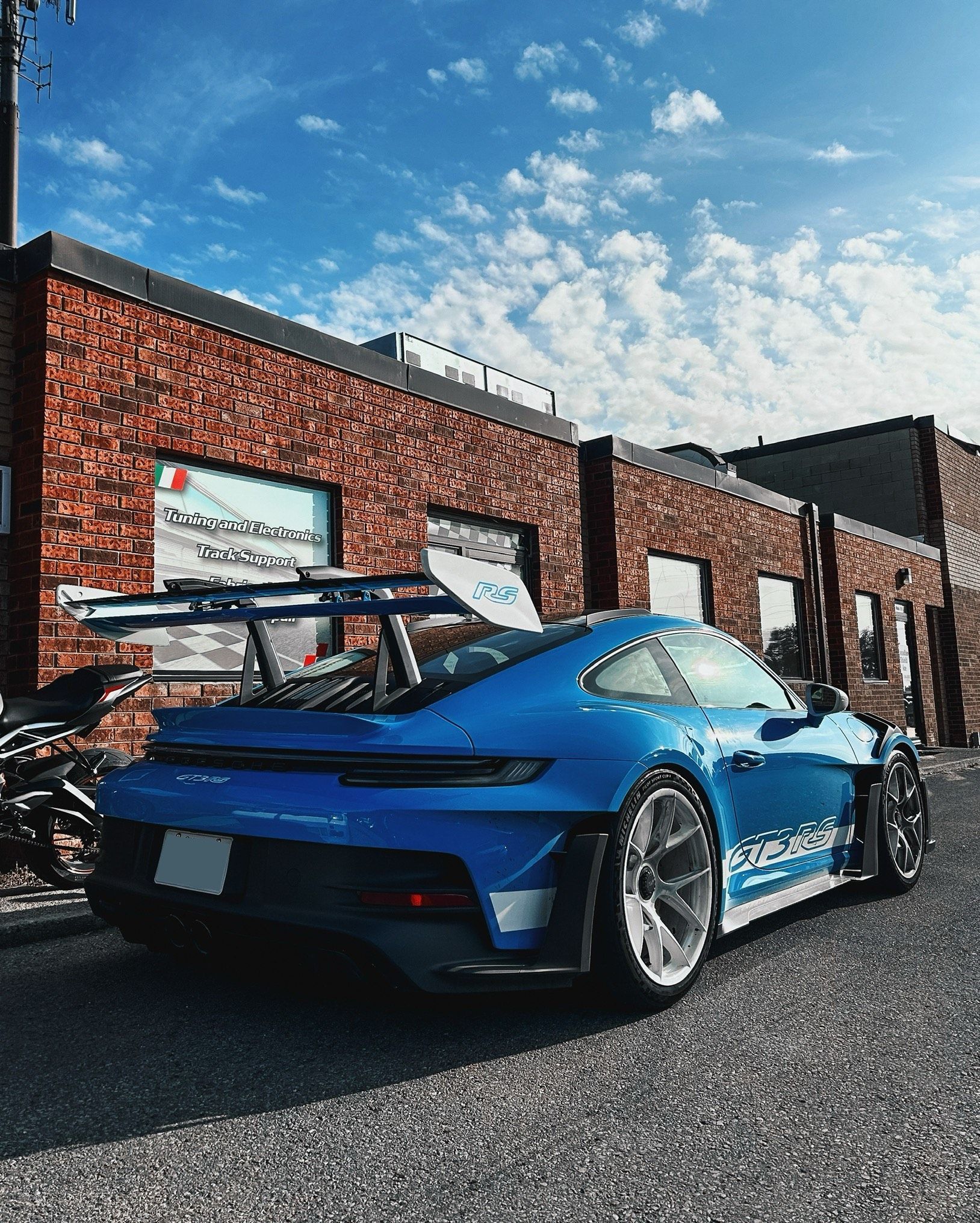 A blue sports car is parked in front of a brick building.