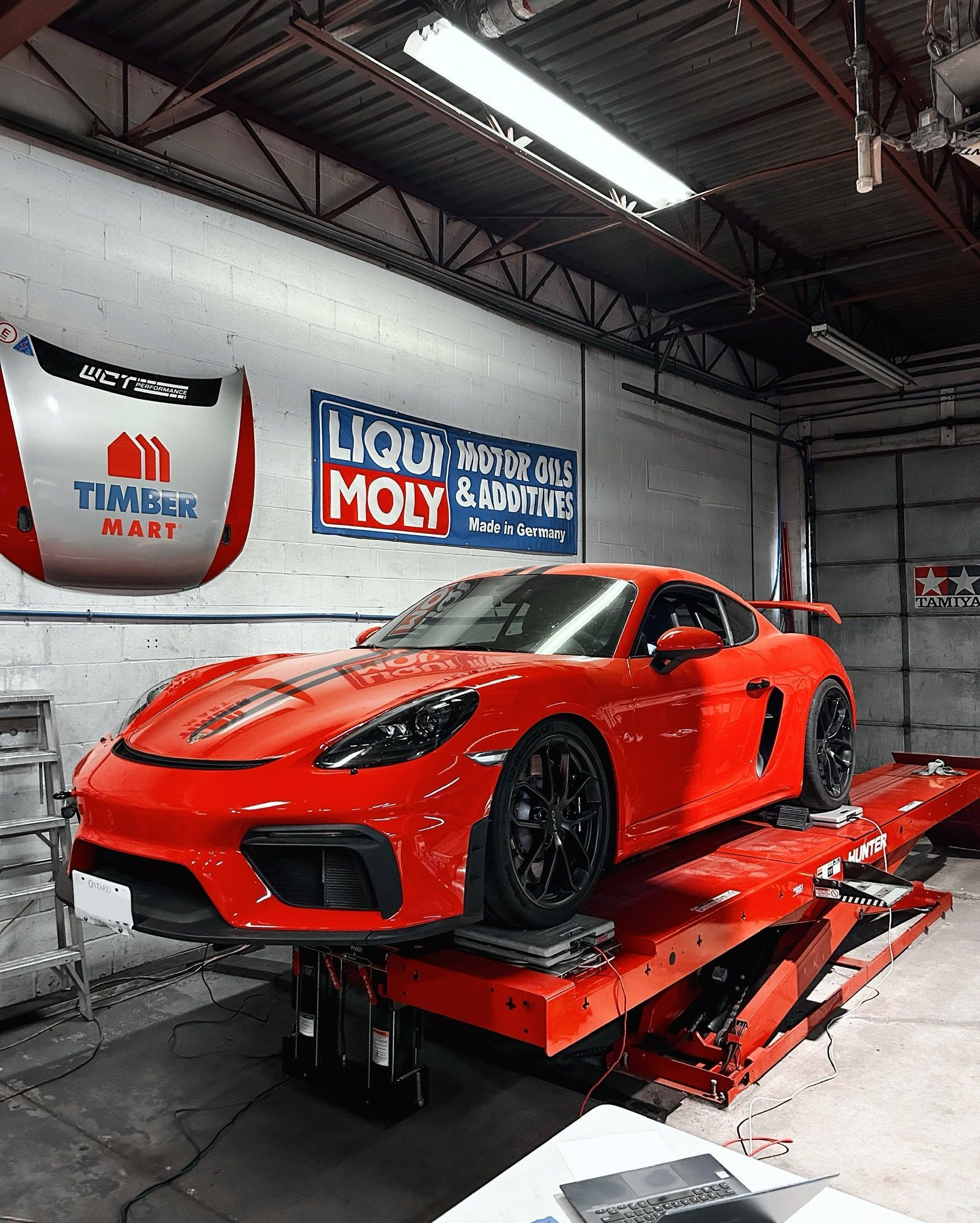 A red sports car is sitting on a lift in a garage.