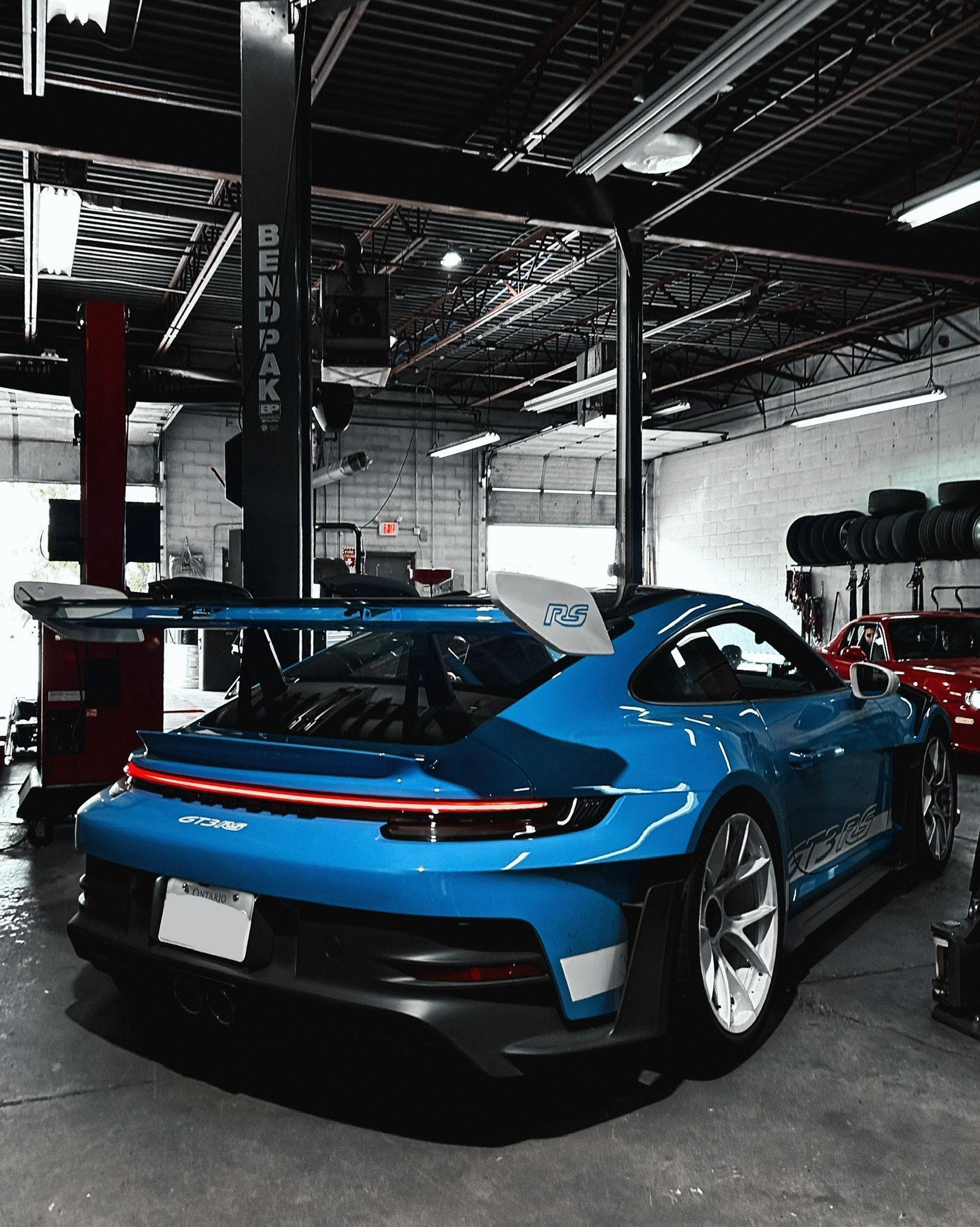 A blue sports car is parked in a garage on a lift.