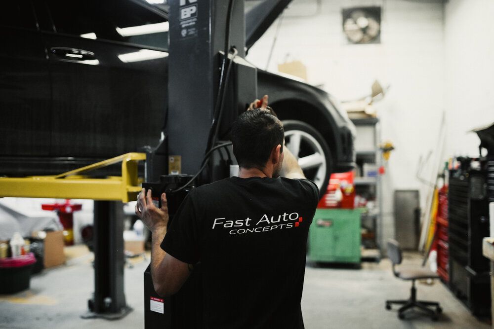 A man is working on a car on a lift in a garage.