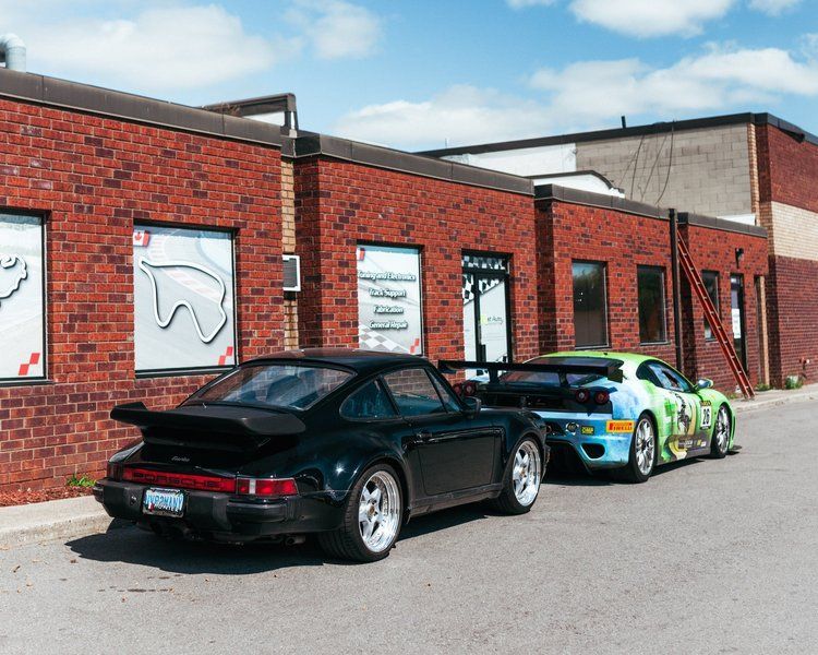 Two sports cars are parked in front of a brick building.