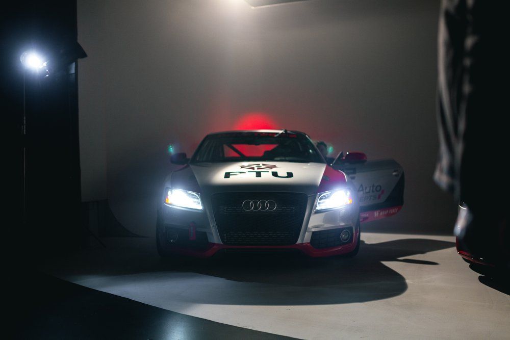 A car is parked in a dark room with its doors open.