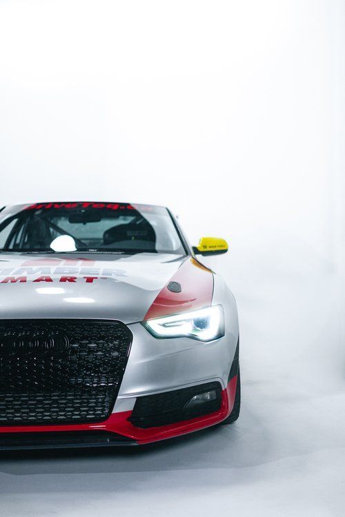 A silver and red sports car is parked on a white surface.
