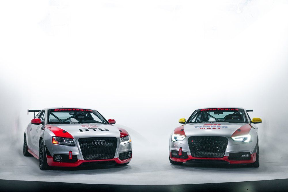 Two racing cars are parked next to each other on a white background.