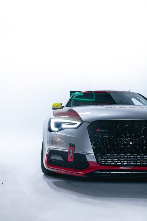 A close up of a silver and red sports car on a white background.