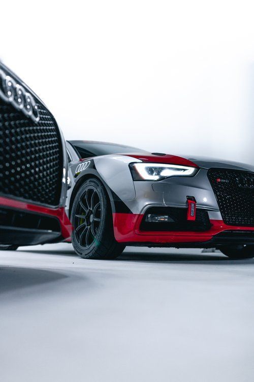 A couple of cars are parked next to each other on a white surface.