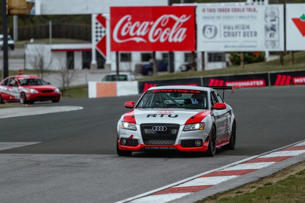 A race car is driving down a track in front of a coca cola sign.