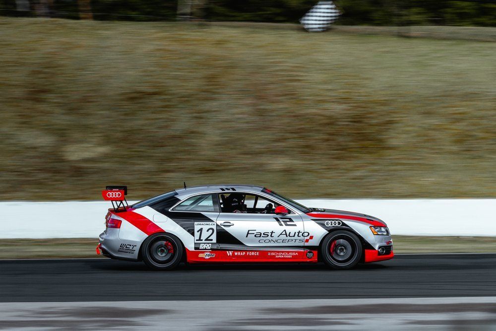 A red and white race car is driving down a race track.