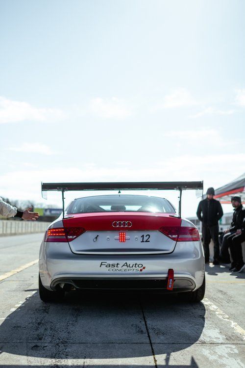 A silver and red audi a4 is parked on a race track.