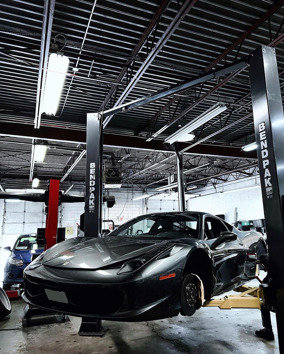 A car is sitting on a lift in a garage.