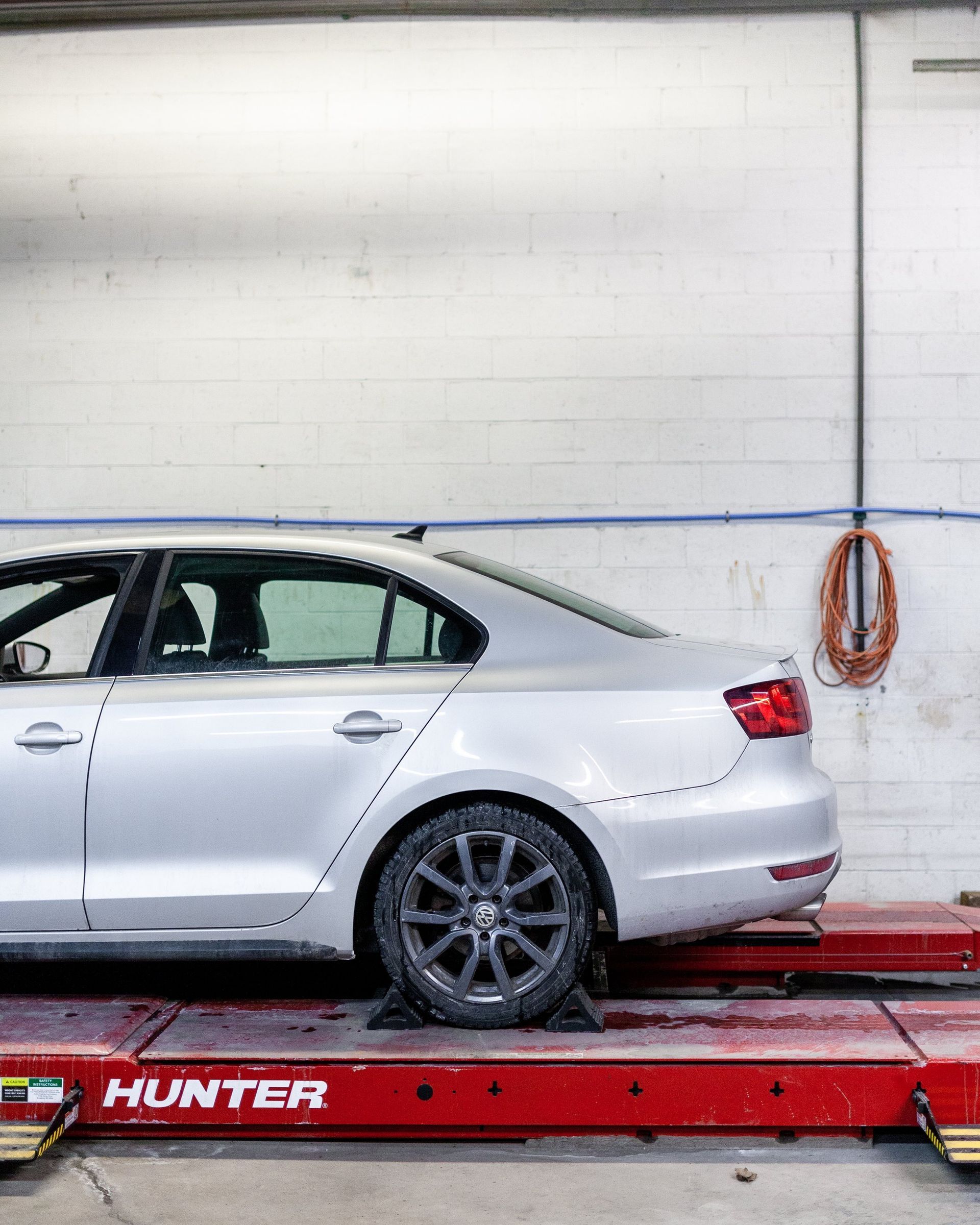A silver car is sitting on top of a red lift in a garage.