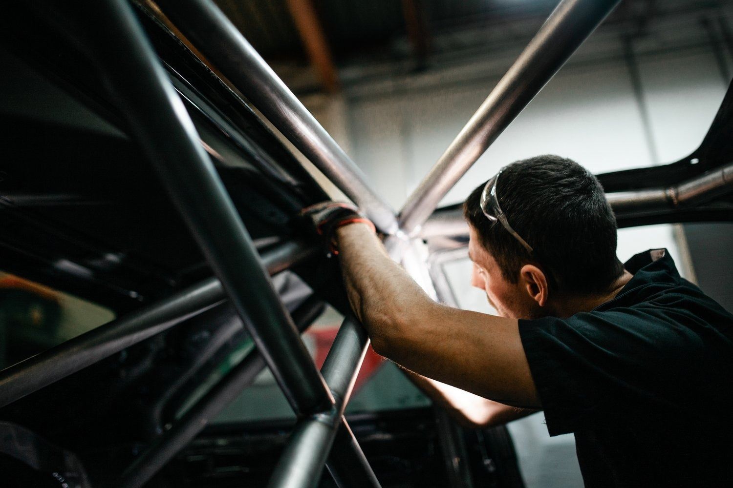 A man is working on a metal structure in a garage.