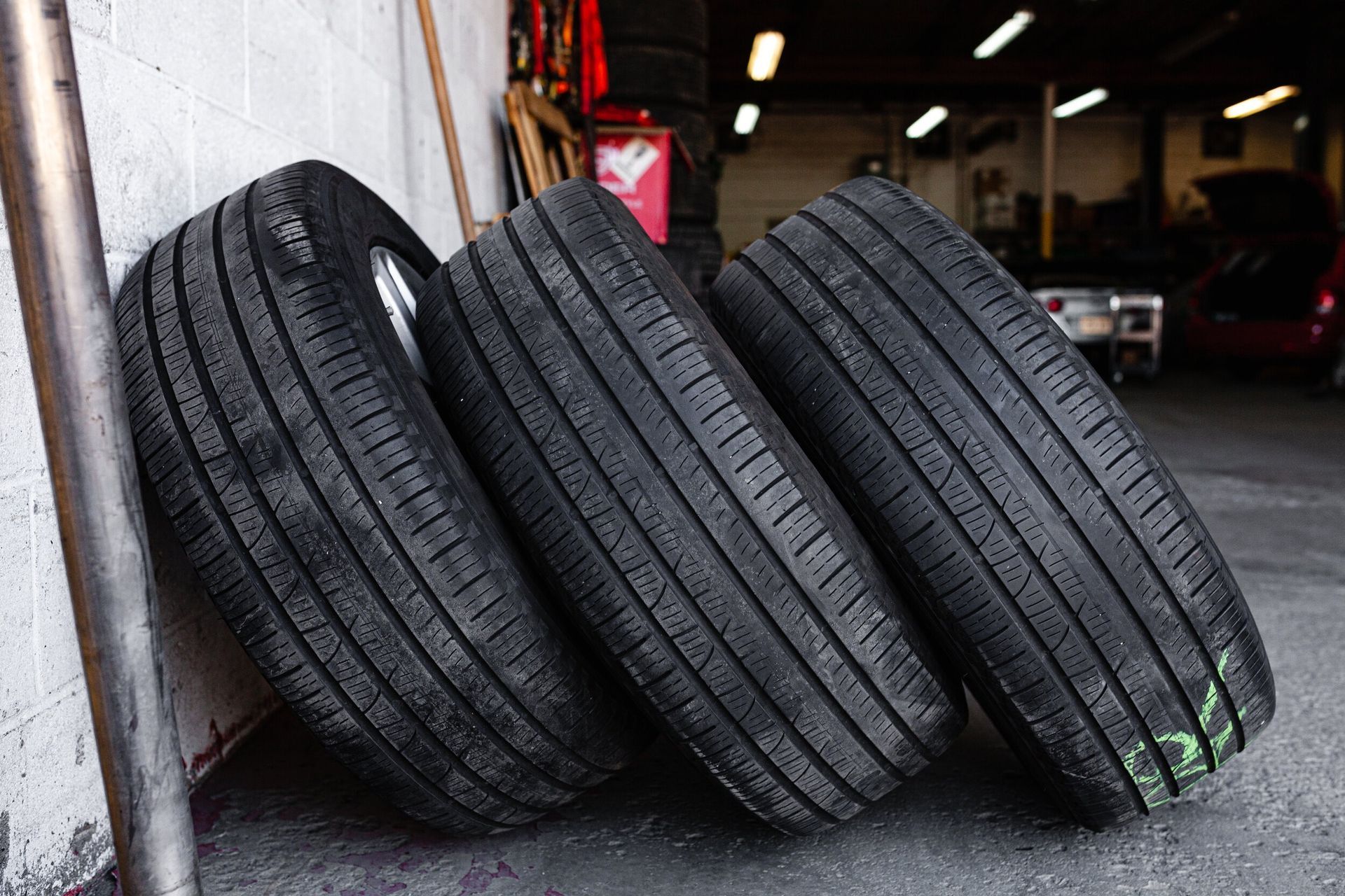 Three tires are stacked on top of each other in a garage.