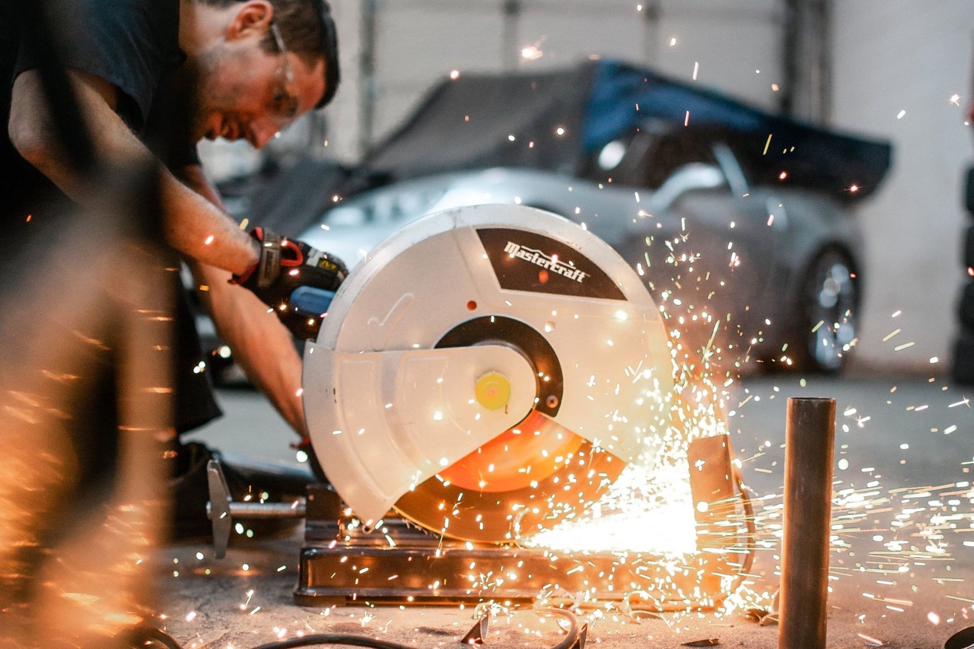 A man is cutting a piece of metal with a circular saw.