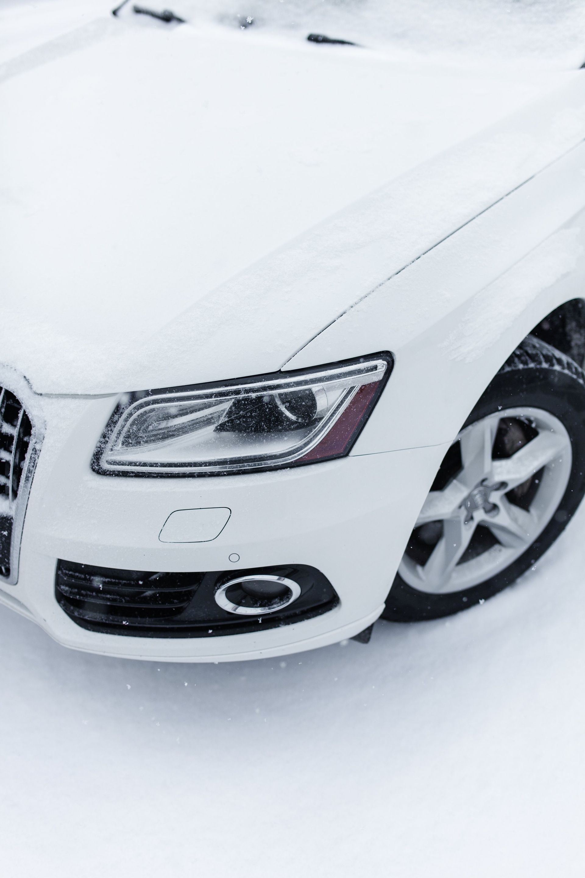 A white car is parked in the snow.