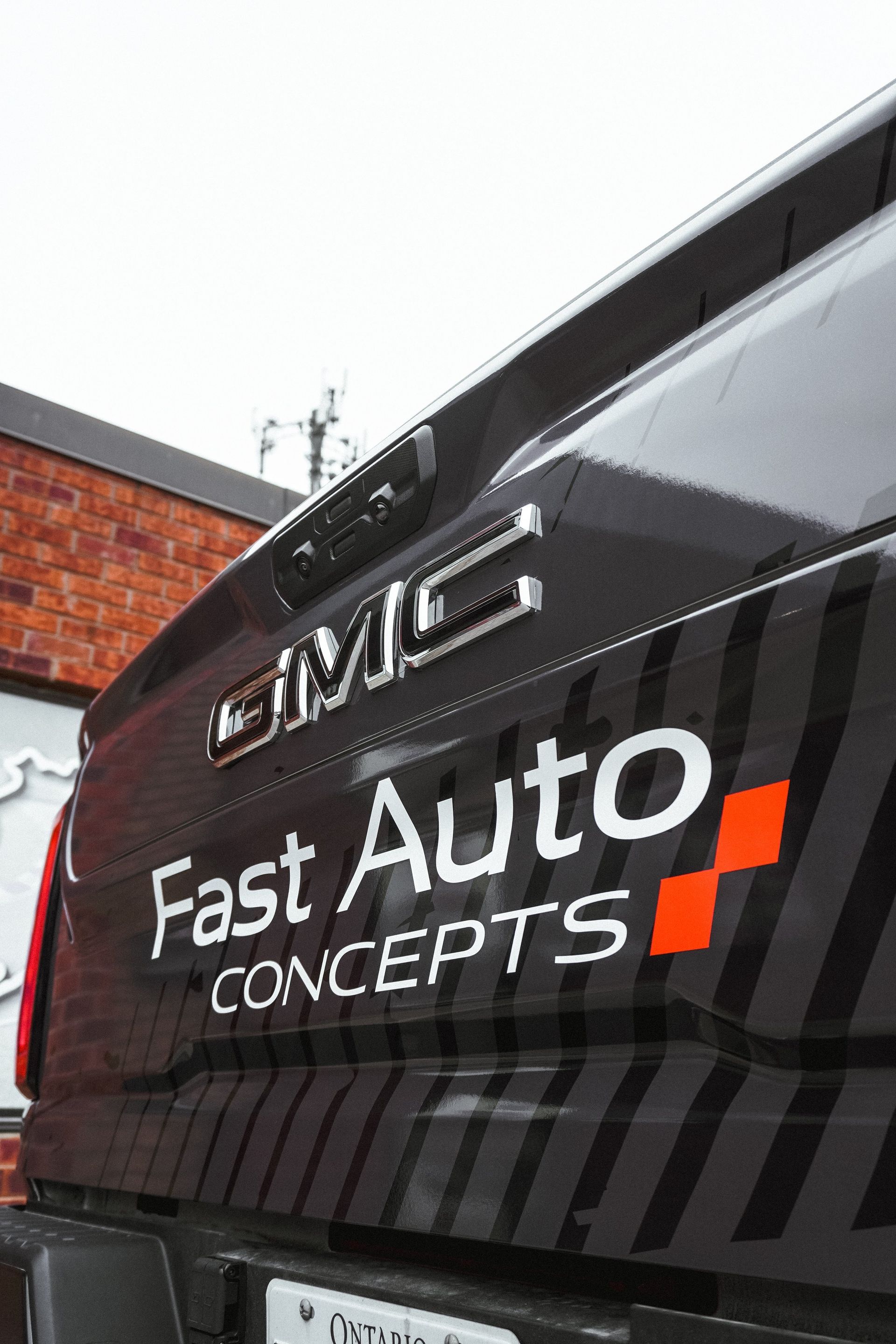 A black gmc fast auto concepts truck is parked in front of a brick building.