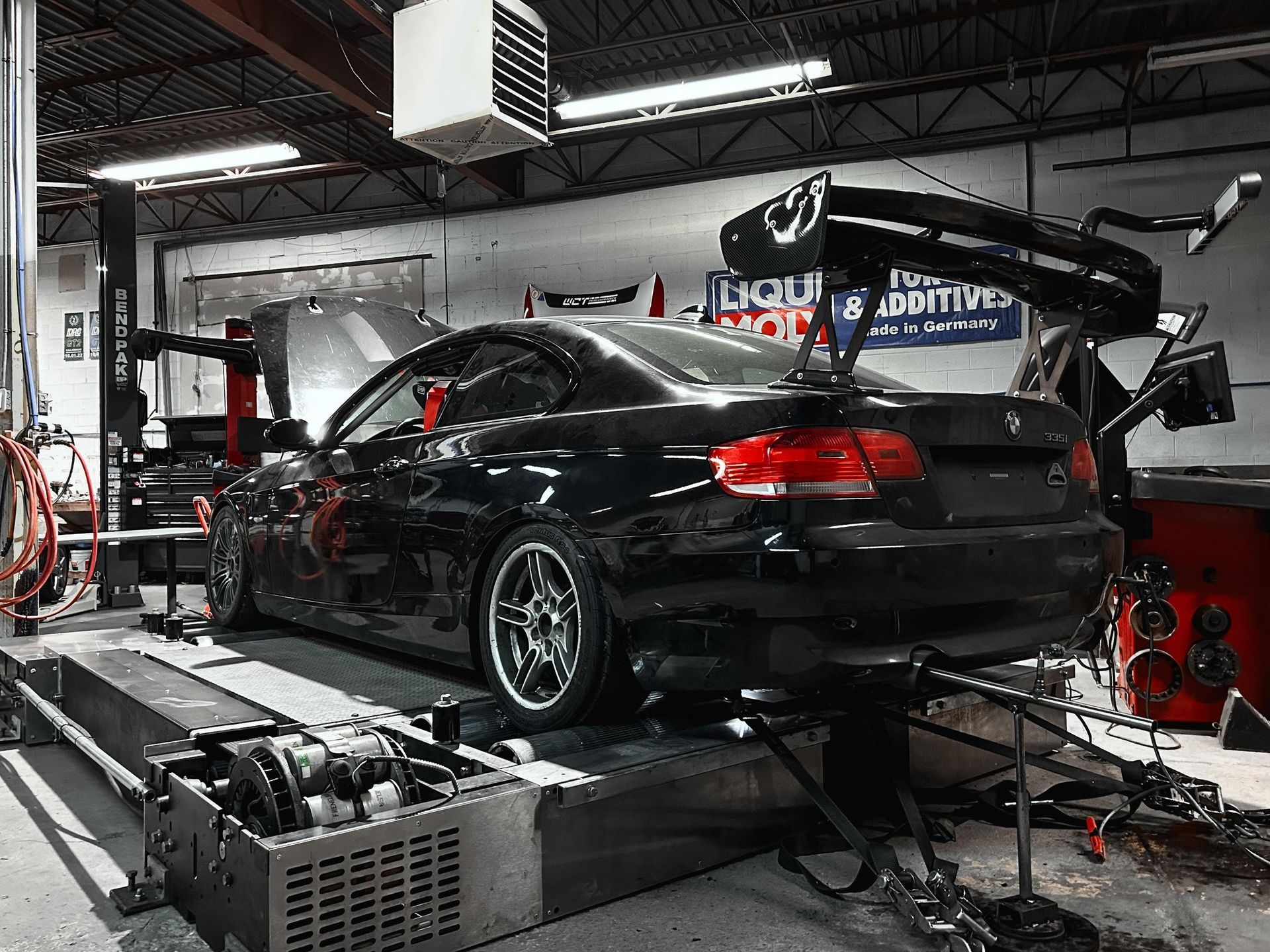 A black car is sitting on a lift in a garage.