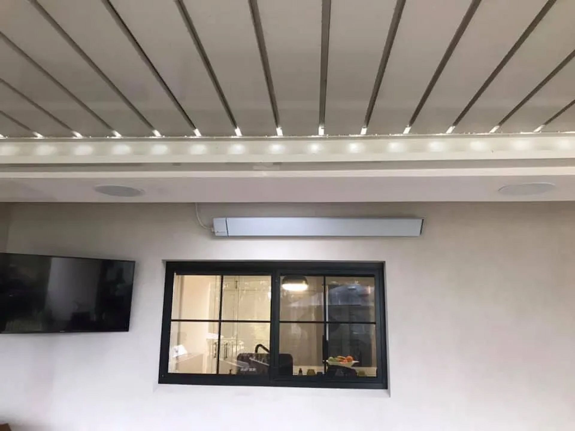 Modern room interior with a wall-mounted TV, window, and ceiling lights — Technik Electrical in Renwick, NSW