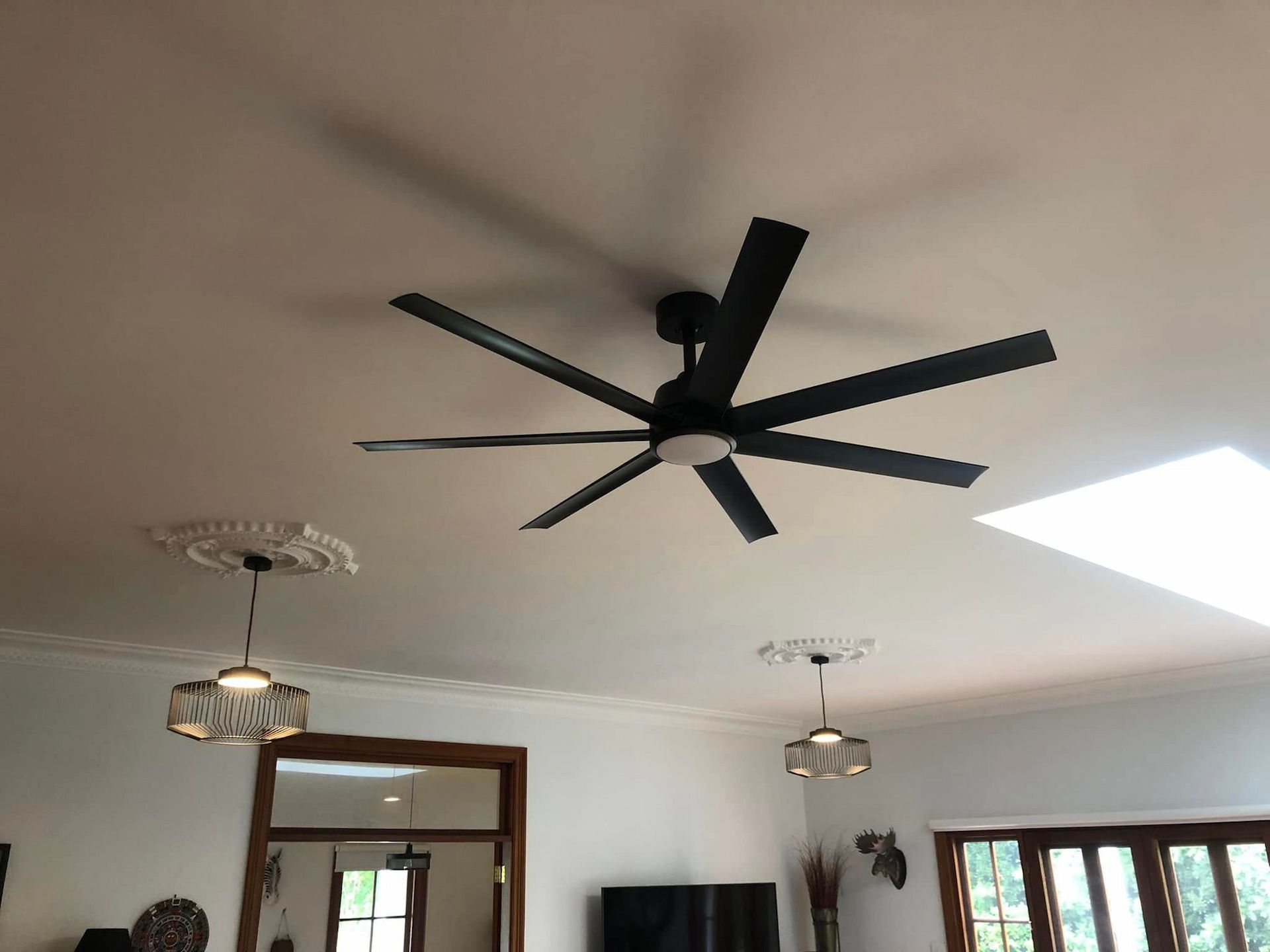 Interior ceiling with a large black modern fan and two hanging lights above a room with windows. — Technik Electrical in Bundanoon, NSW
