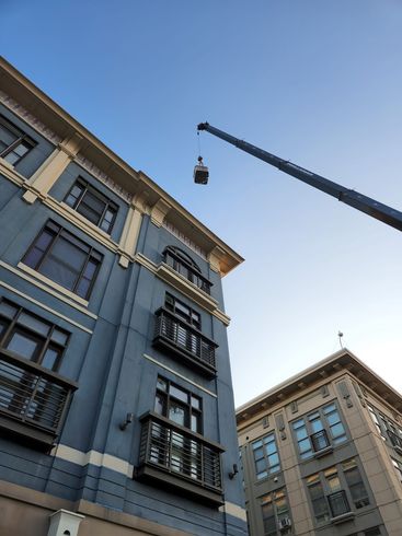 Buildings with balconies and a crane against a blue sky.