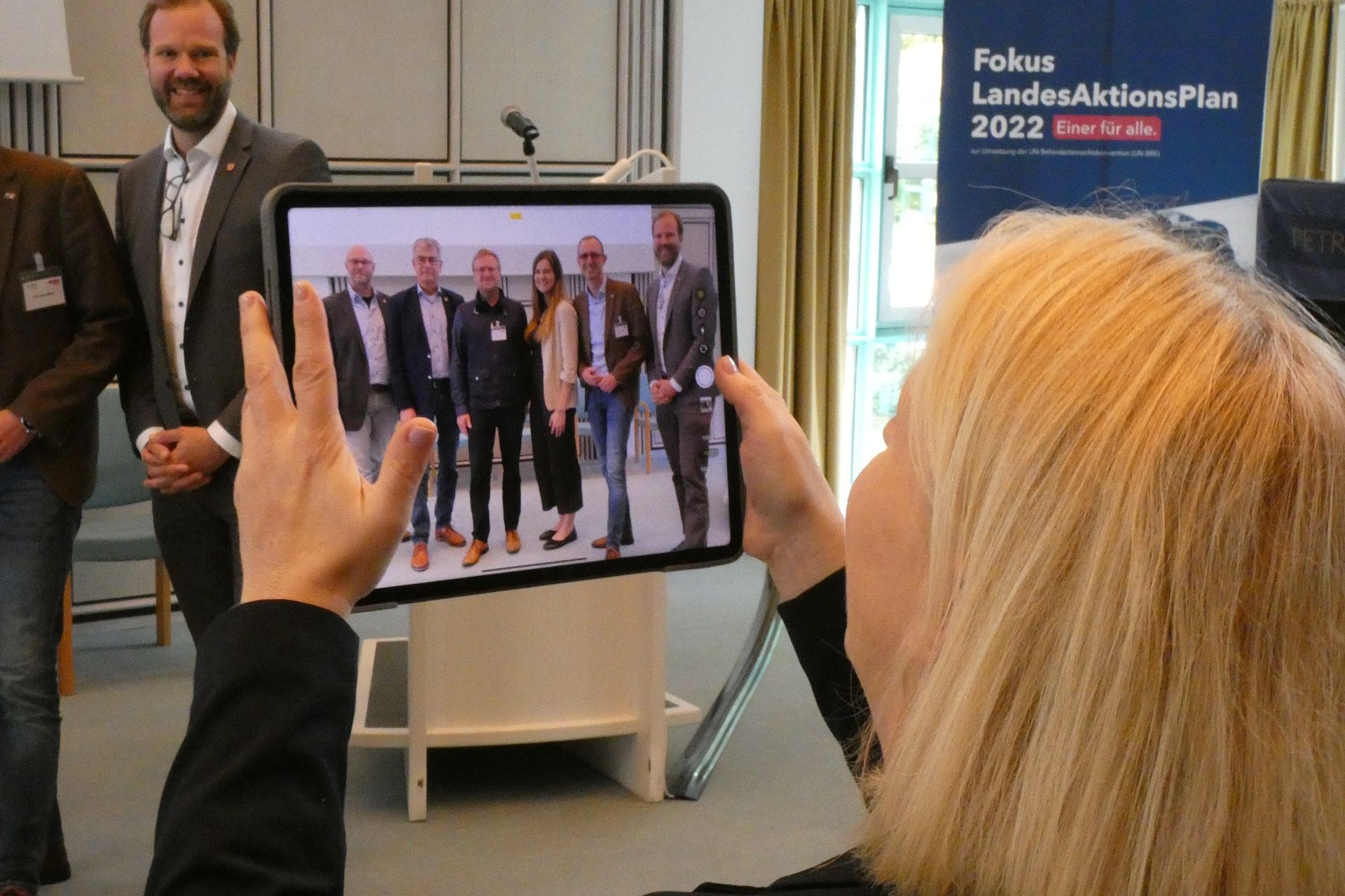 Bild, wie jemand mit einem Ipad ein Bild von verschiedenen Personen macht