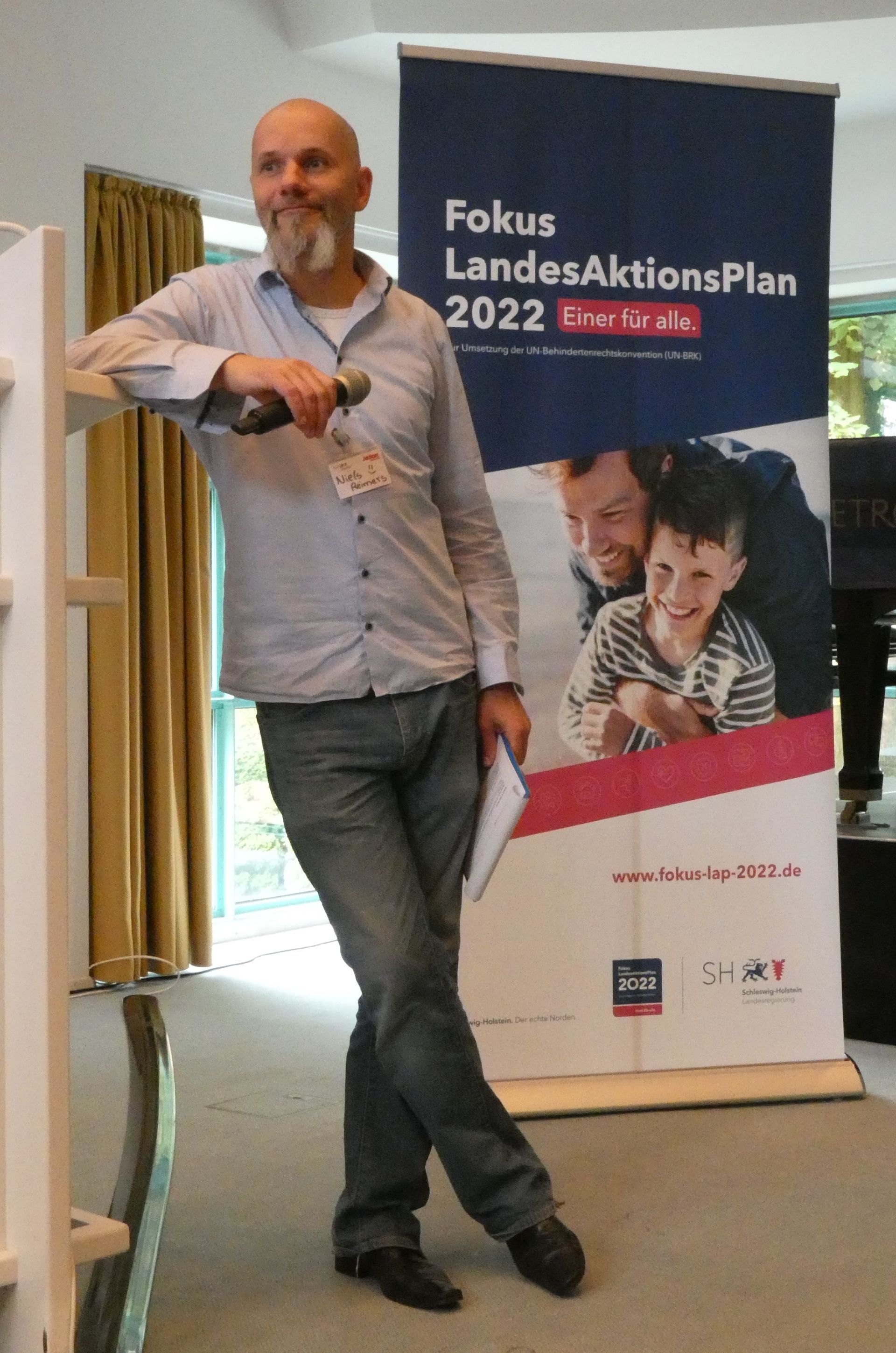 Bild vom Moderator, wie er am Rednerpult lehnt.