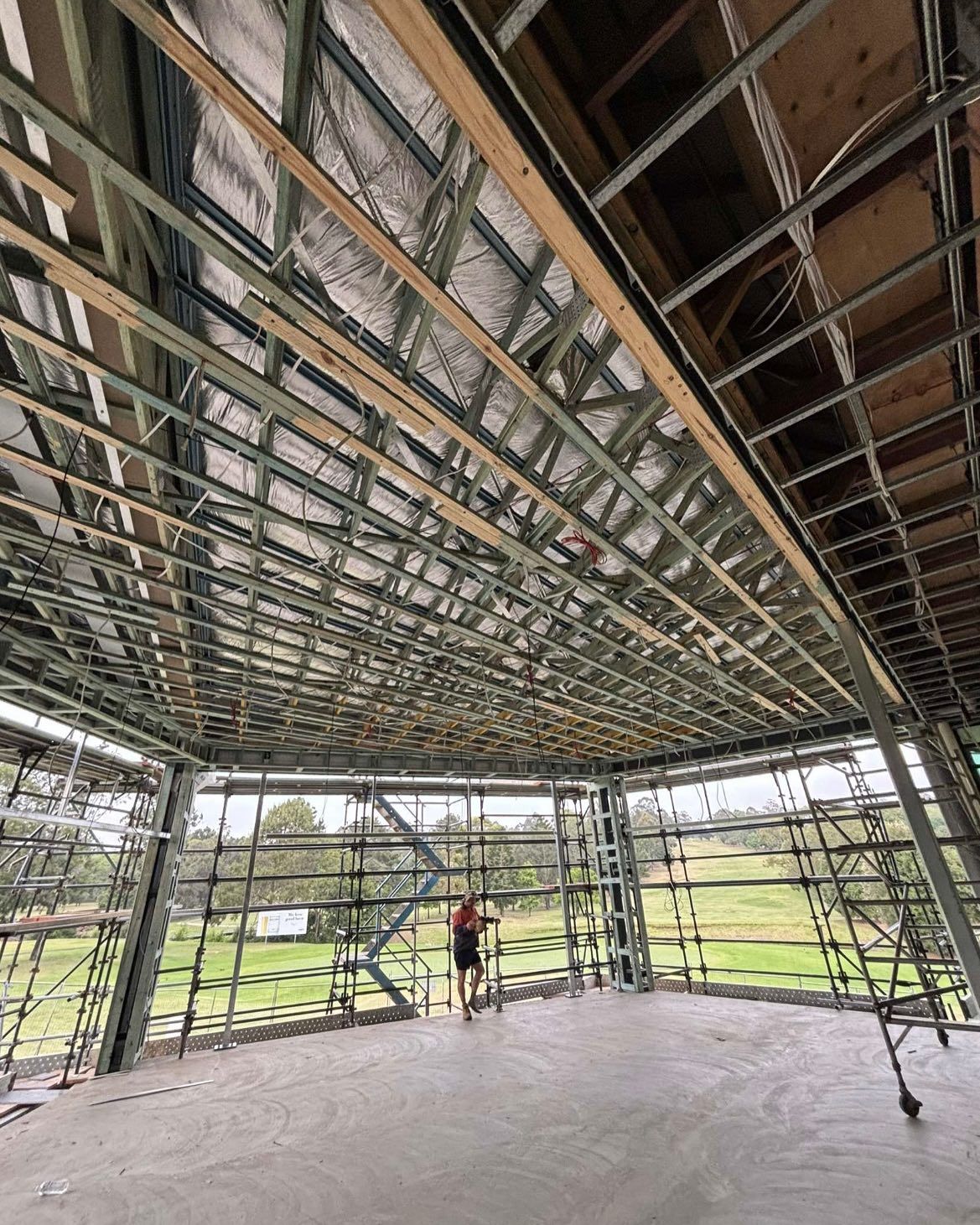 Interior view of a building under construction, featuring metal framing and insulation. A person stands inside the frame.