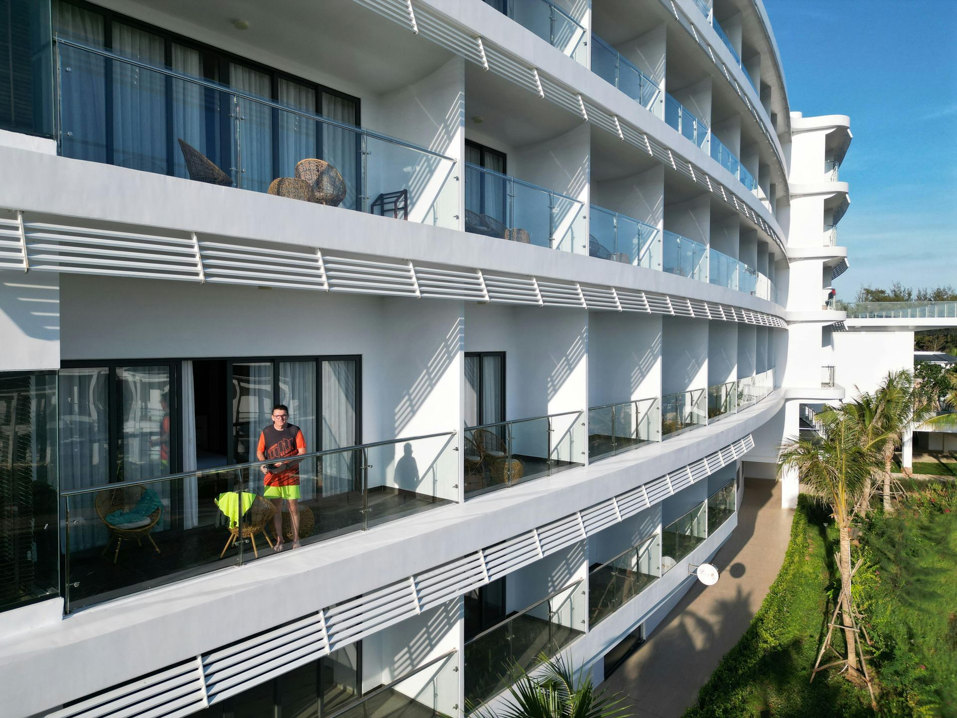 A man is sitting on a balcony of a hotel.