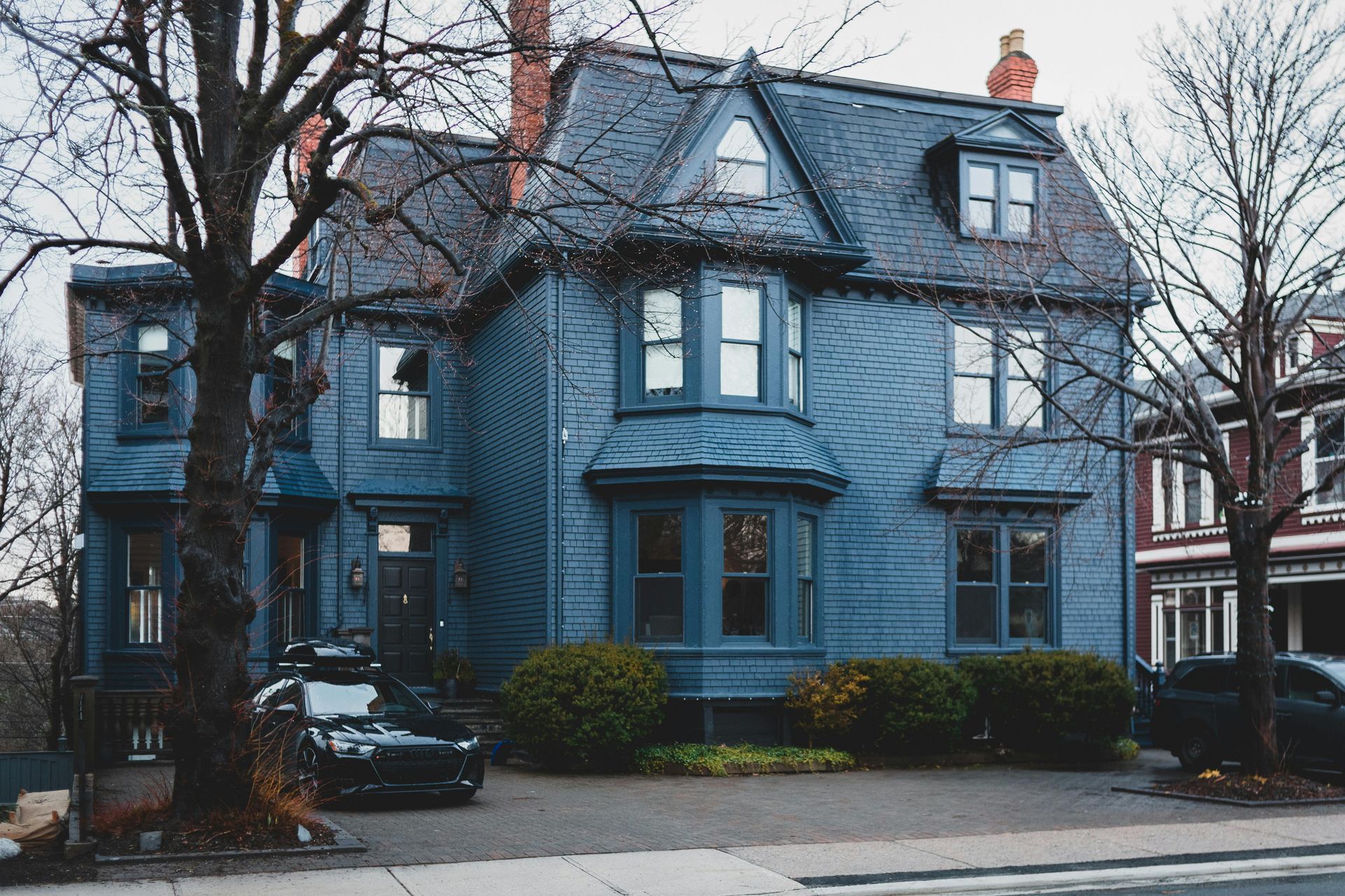 A blue house with a black car parked in front of it