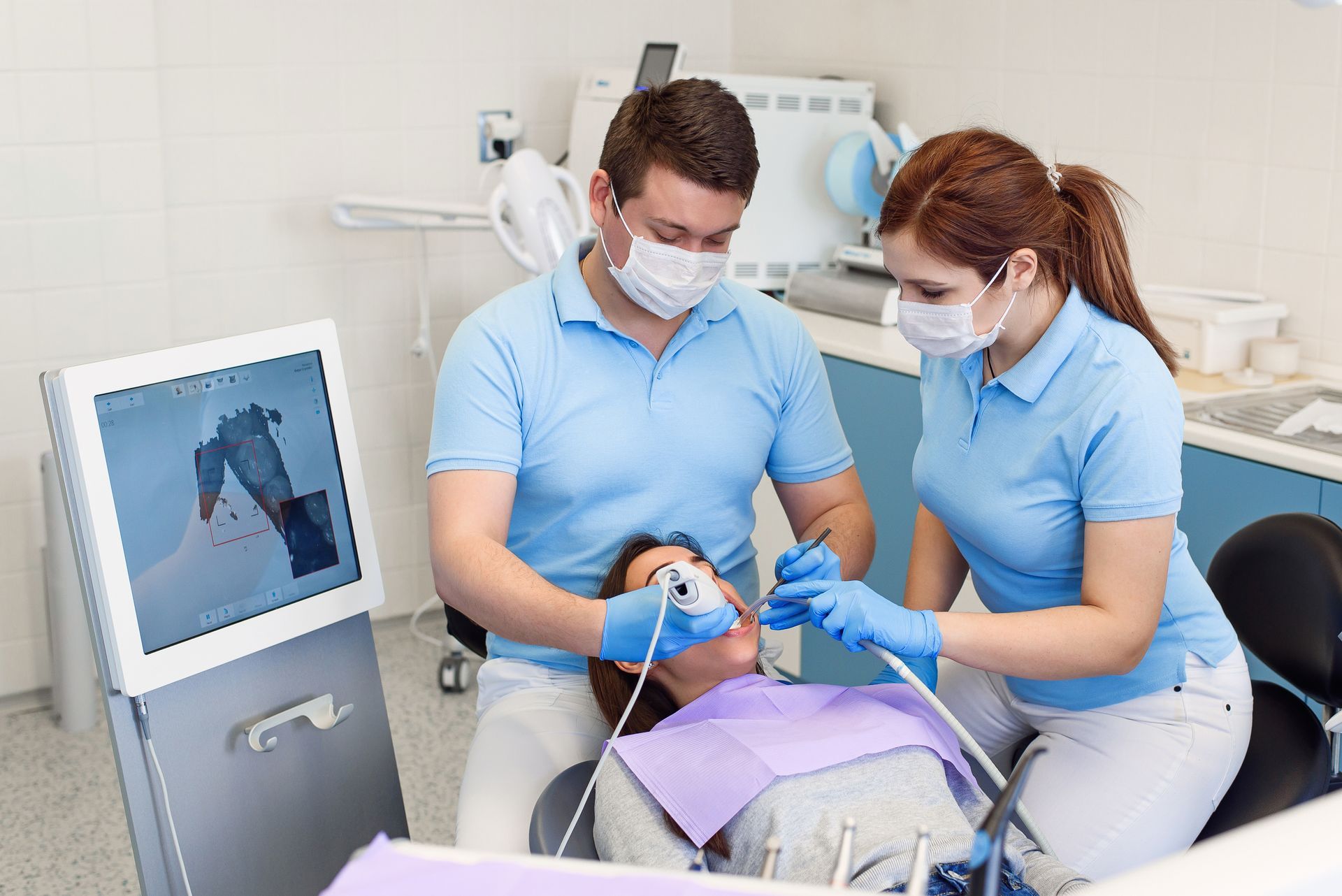Two dentists are examining a patient 's teeth in a dental office.