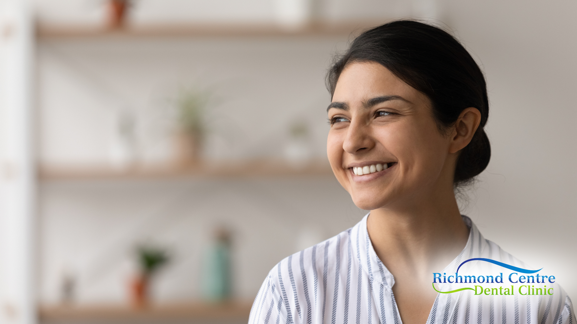 A woman is smiling and looking away from the camera.