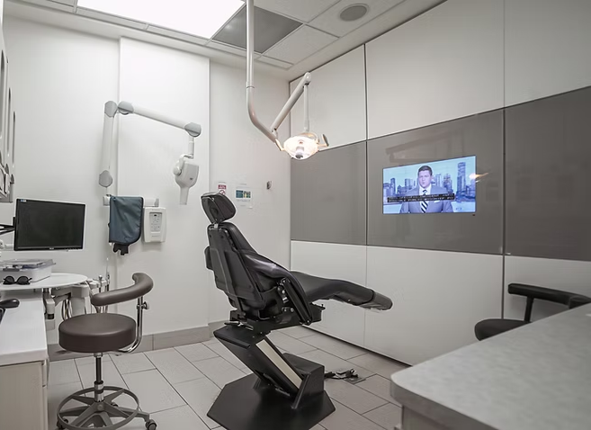 A dental office with a dental chair and a television on the wall.