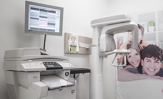 A dental office with a computer , printer , and x-ray machine.