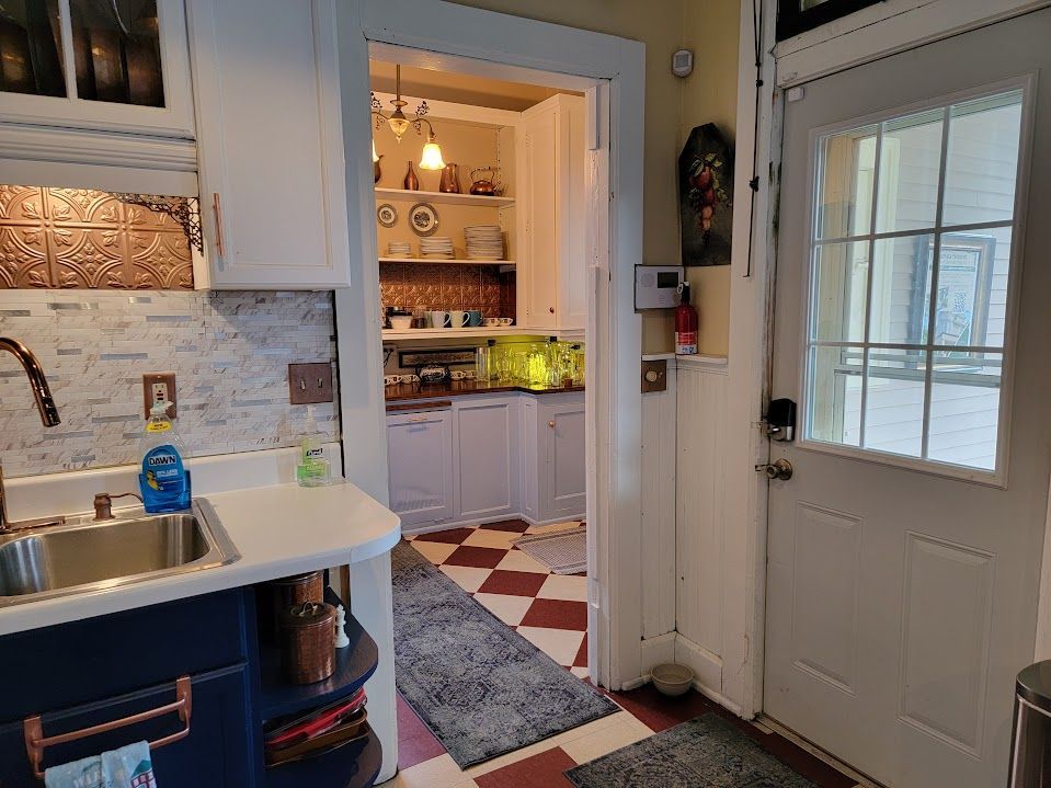 Kitchen with blue cabinets, a sink, and a doorway leading to a second kitchen with red and white checkered floors.
